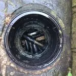 A blocked outdoor drain gully with debris inside