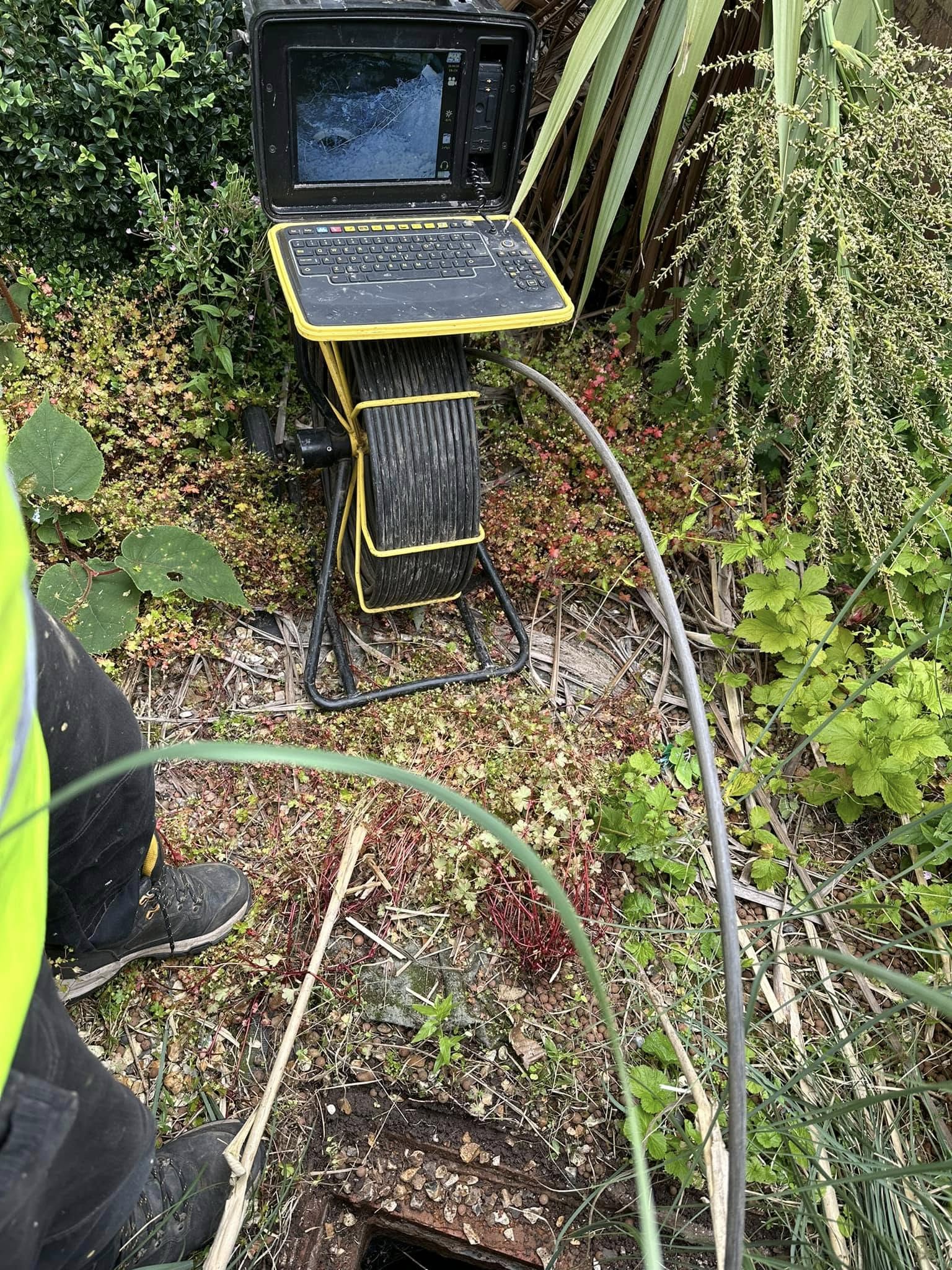 CCTV drain survey equipment and monitor being used by an engineer in a garden.