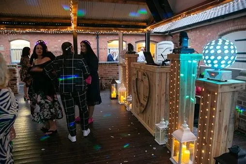 Guests dancing at a lively party with a professional DJ setup.