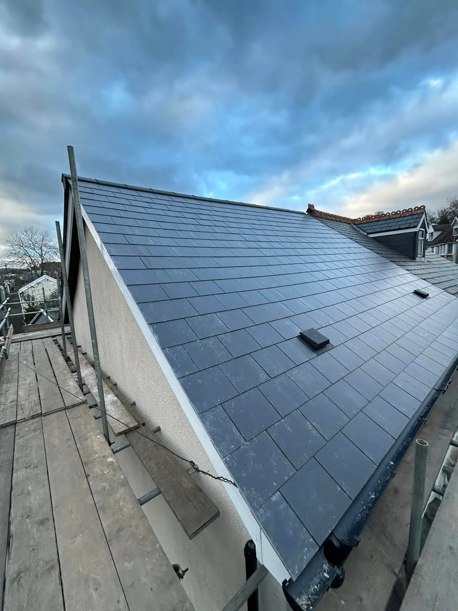 Newly installed tiled pitched roof with scaffolding on a house.