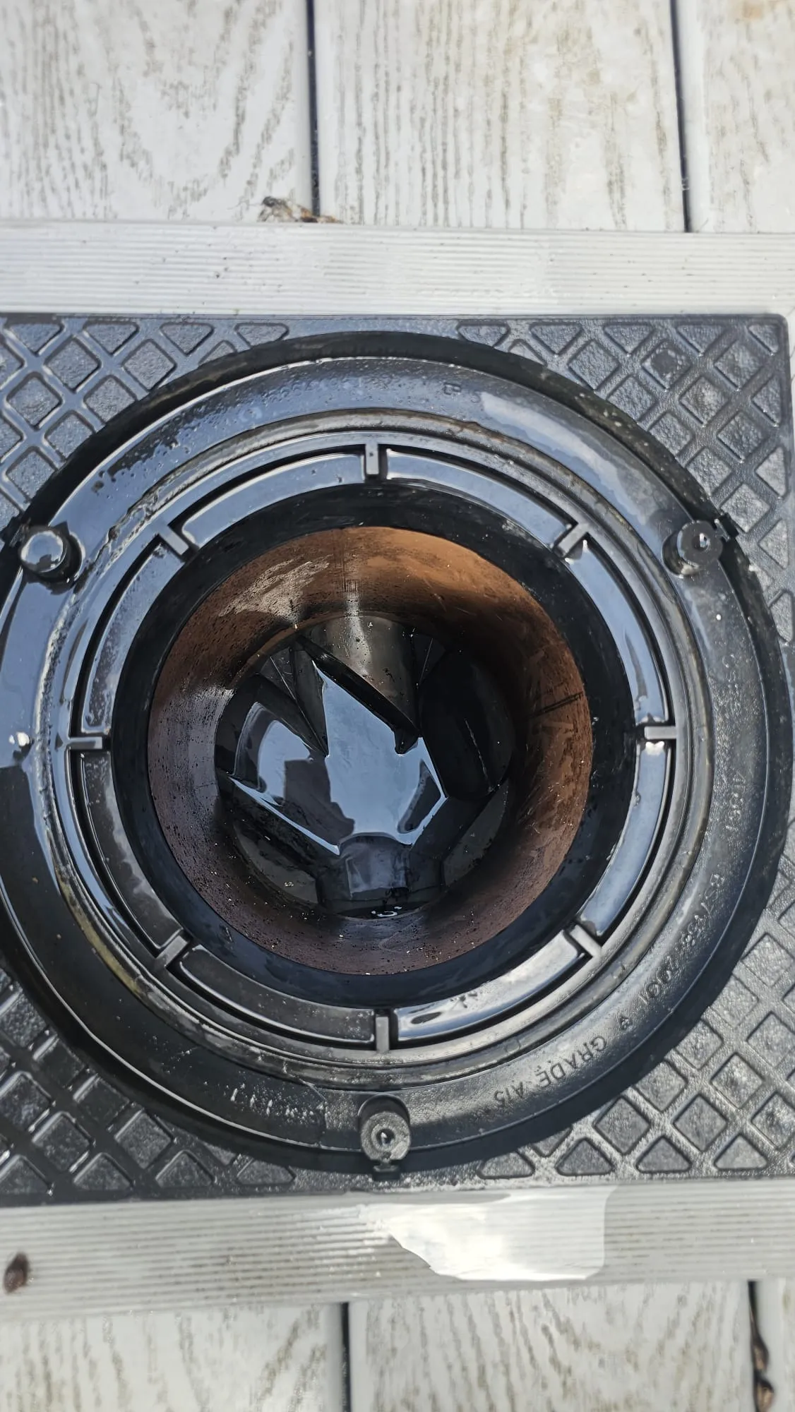 An outdoor drain with standing water, suggesting a blockage or slow drainage.