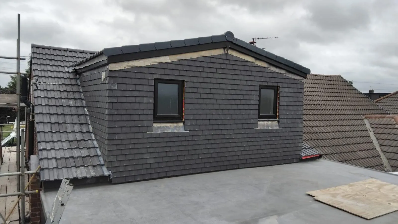A house with a newly constructed dark grey slate dormer and a new flat roof, indicating a recent roof renovation.