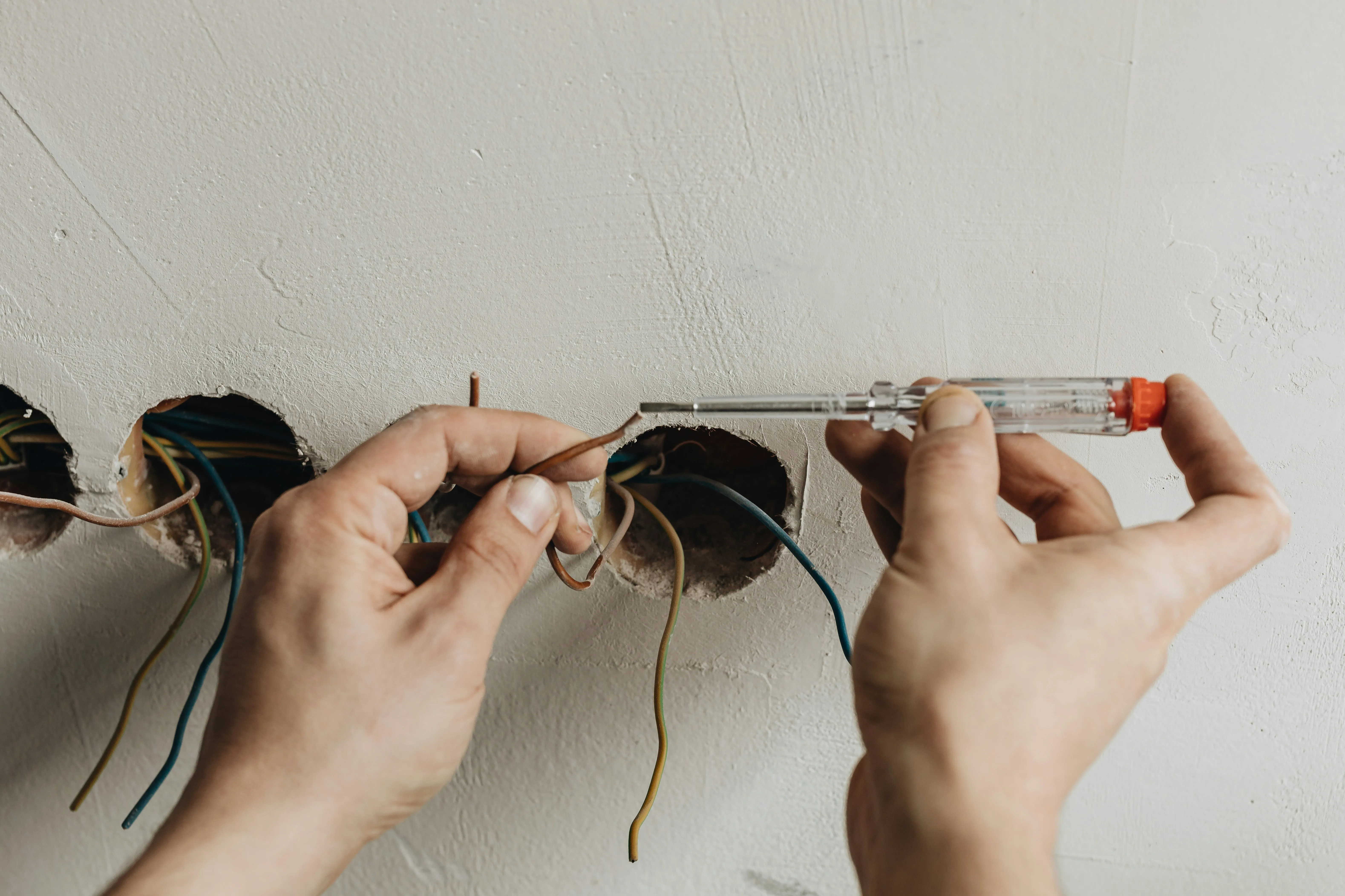 Close-up of an electrician connecting electrical wiring for new sockets in a wall.