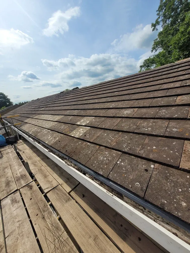 Pitched tiled roof with scaffolding and gutter.