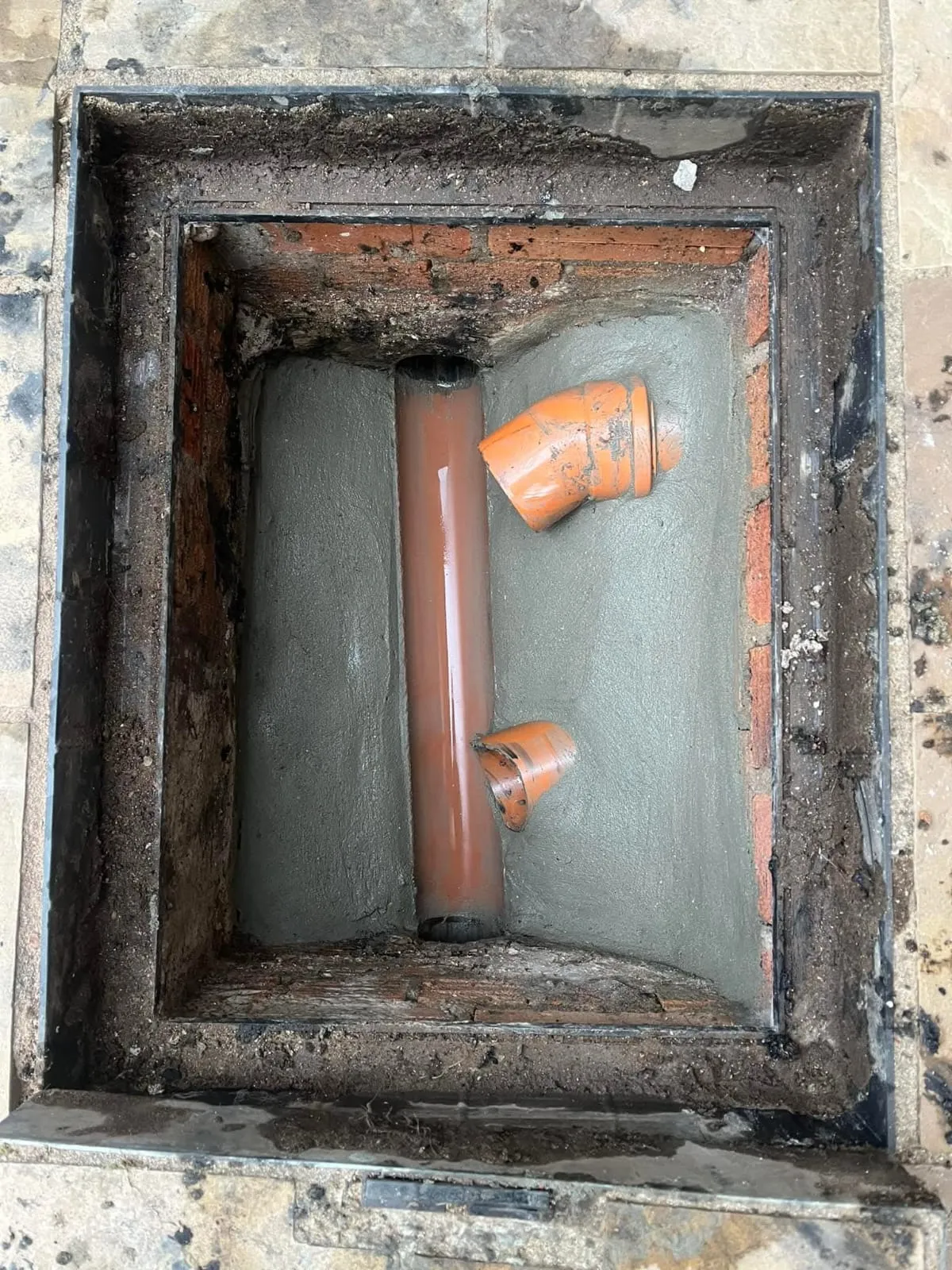 Drainage pipes set in concrete within a manhole access point