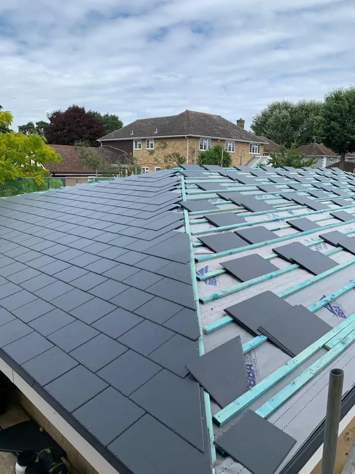New dark grey roof tiles being installed on a residential pitched roof.