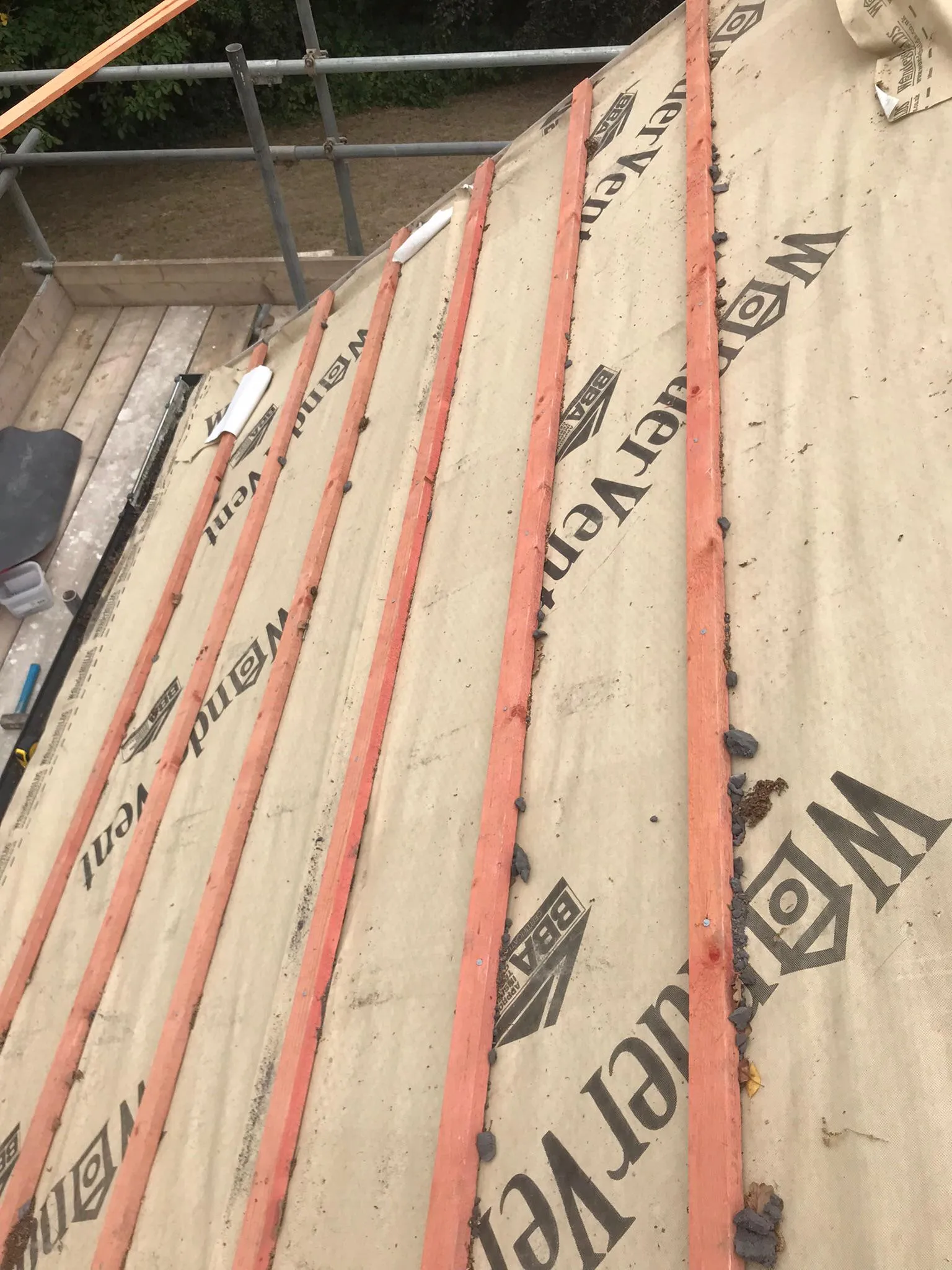 Close-up of a pitched roof in progress, featuring a breathable membrane with branding and timber battens, indicating a new roof installation or repair.