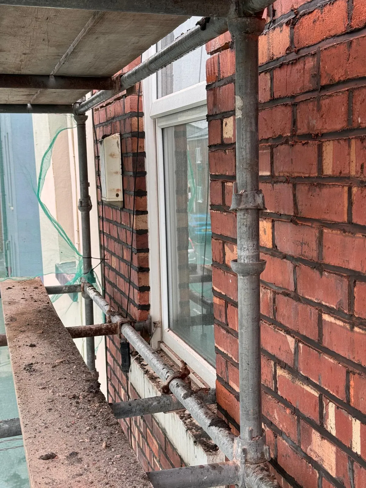 Scaffolding against a brick house wall and window for property maintenance or repairs
