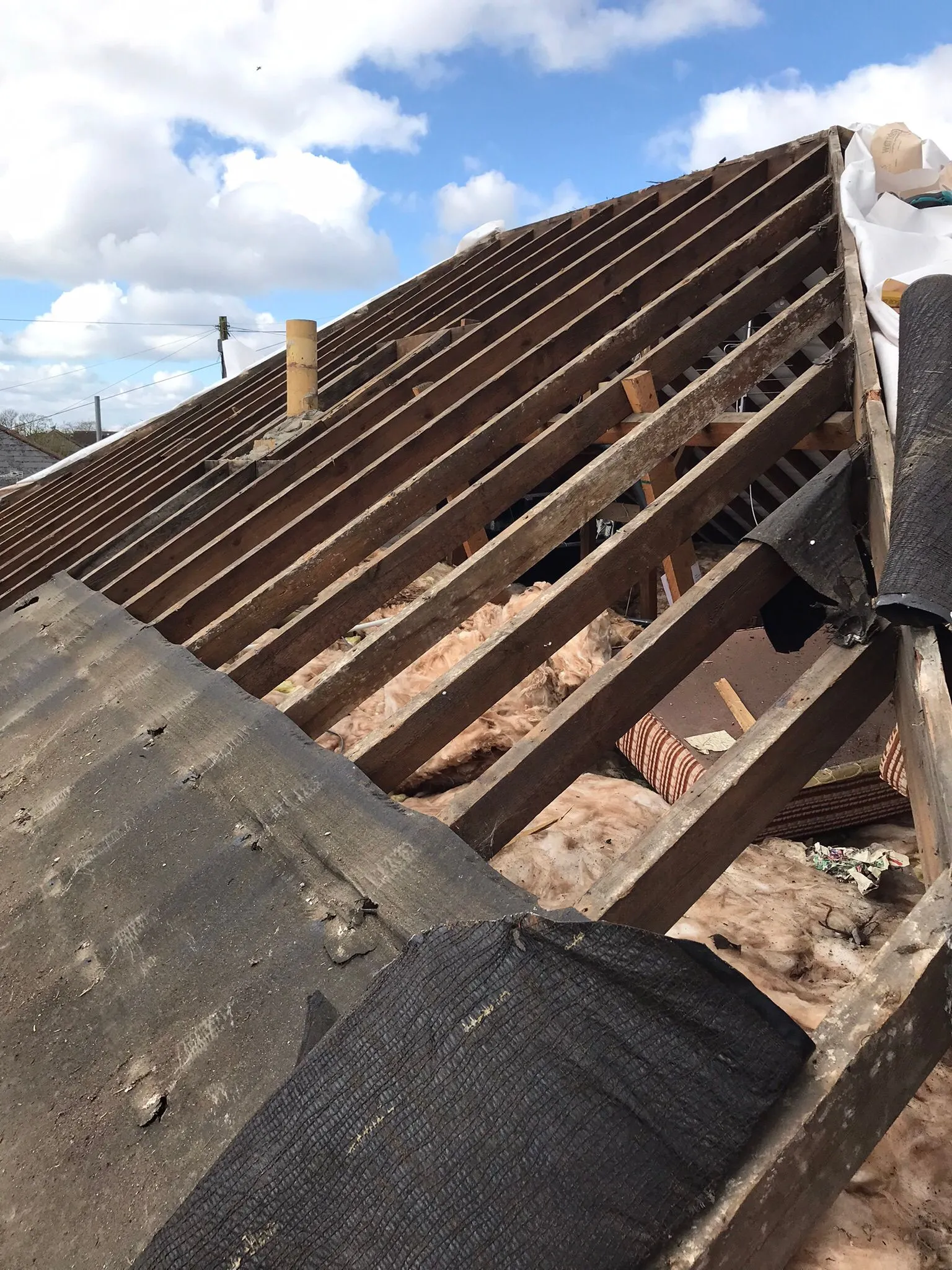 Pitched roof under construction with visible wooden framework, insulation, and protective membrane.