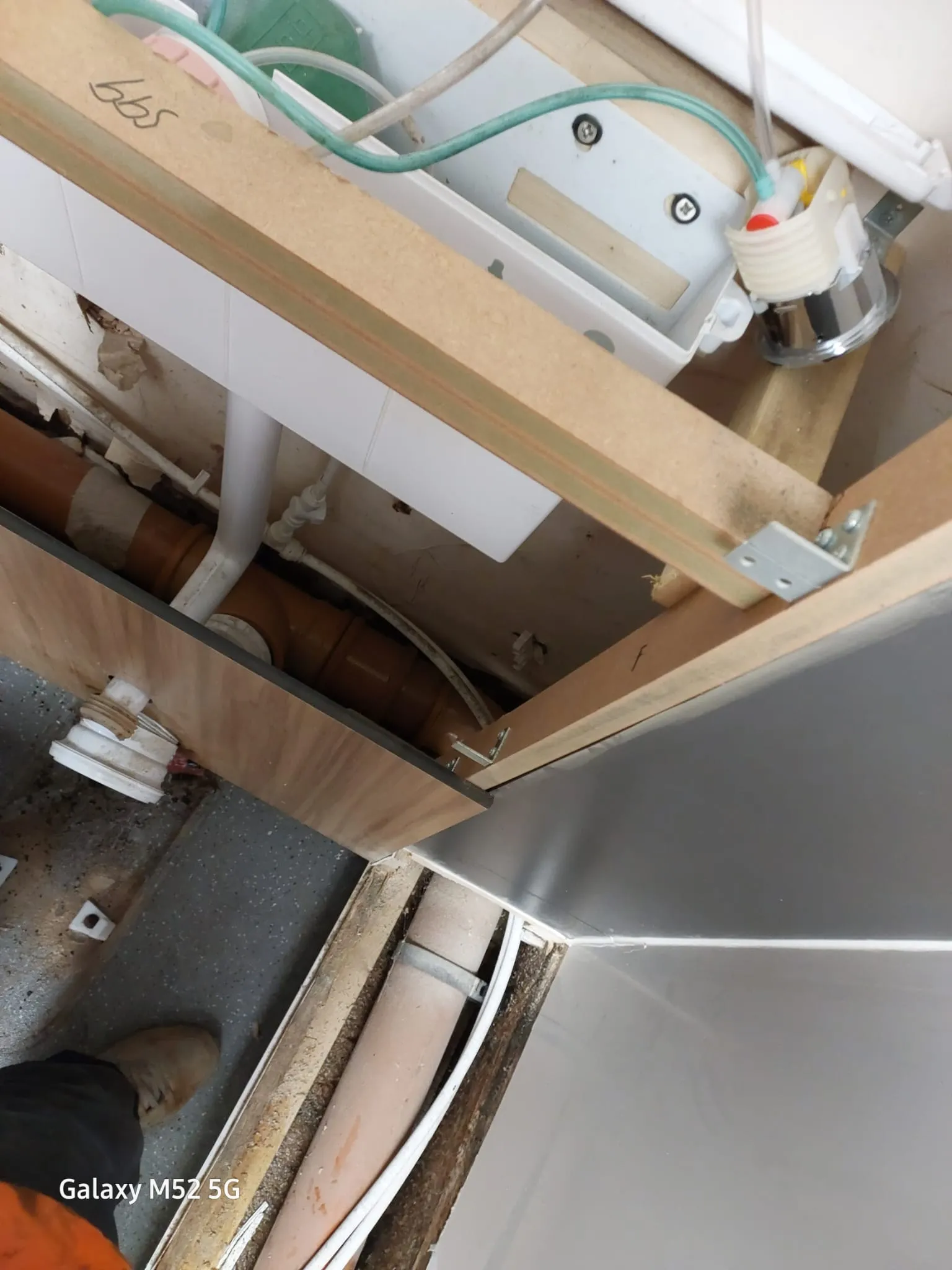 Under-floor view of drainage pipes, electrical wiring, and timber framing during a plumbing installation.