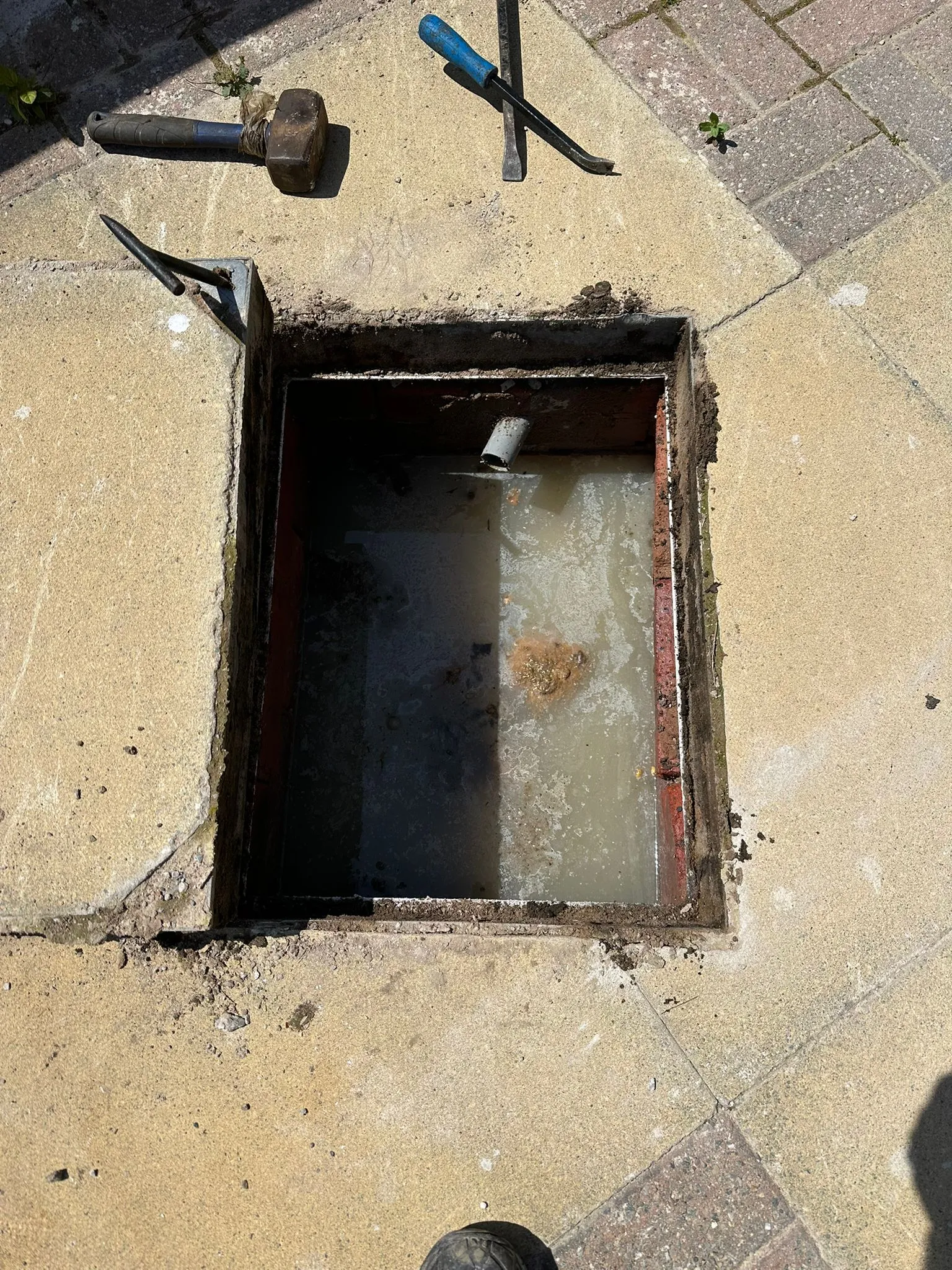 A picture of a blocked drain in an outdoor inspection chamber.