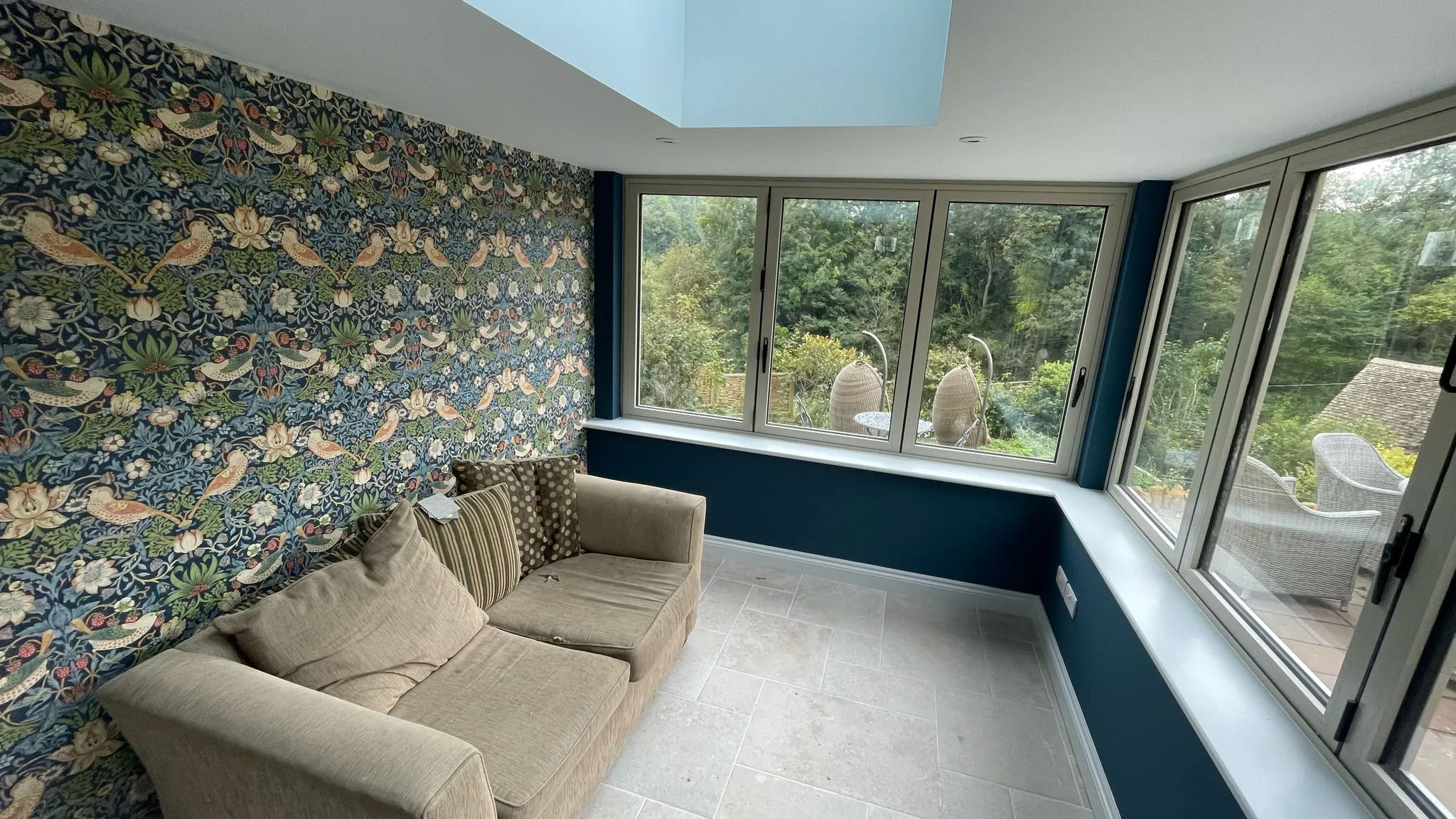 Bright orangery extension interior with large windows and garden view in Gloucestershire.