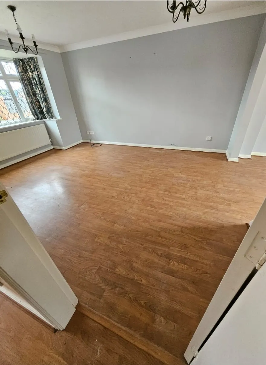 A freshly cleared and clean empty room with wooden laminate flooring and light grey walls, ready for new tenants or occupants after a house clearance service.