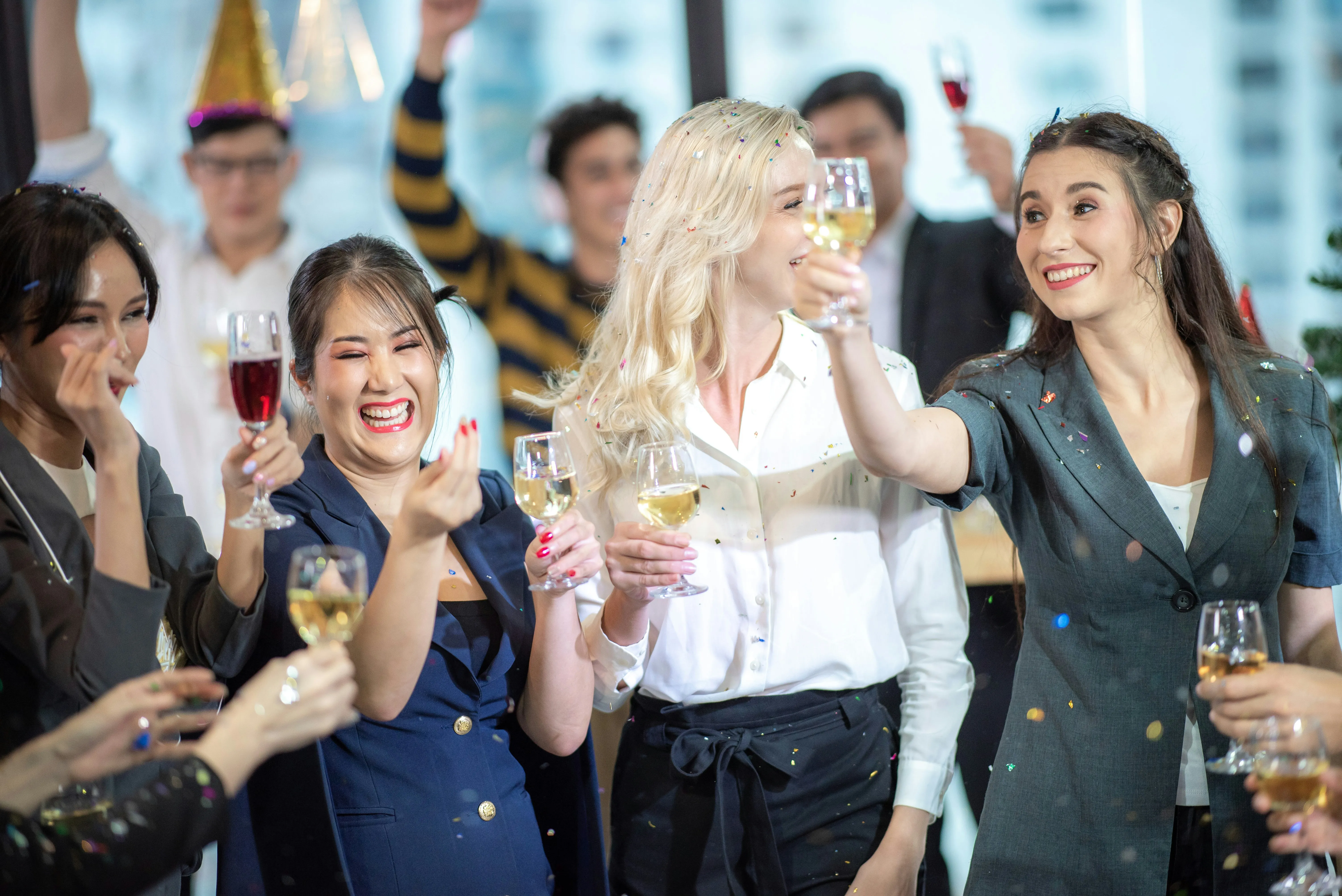 Joyful group celebrating with drinks and falling confetti at a party or event, highlighting a fun and festive atmosphere.