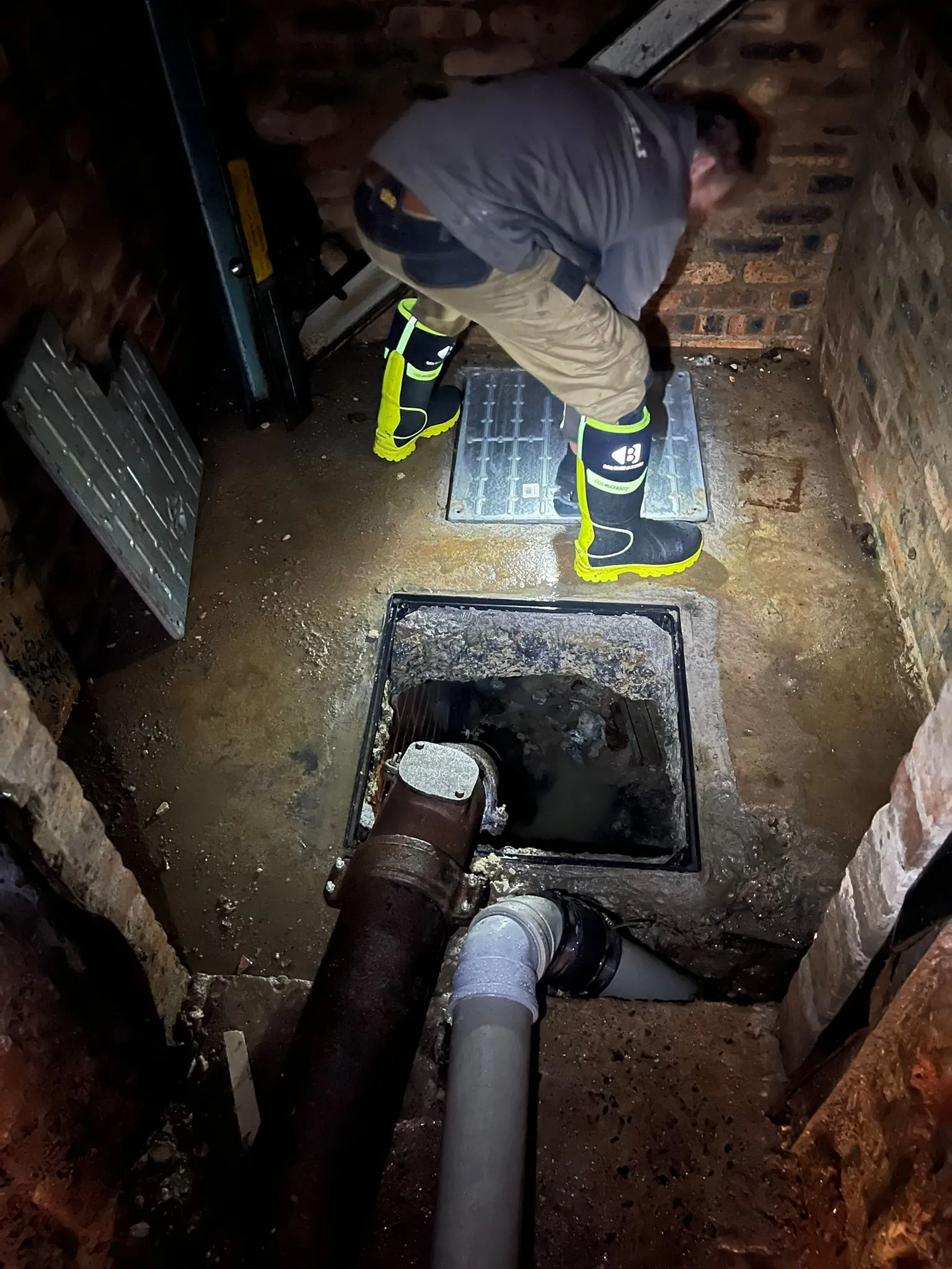 Drainage engineer inspecting or unblocking an outdoor drain or manhole
