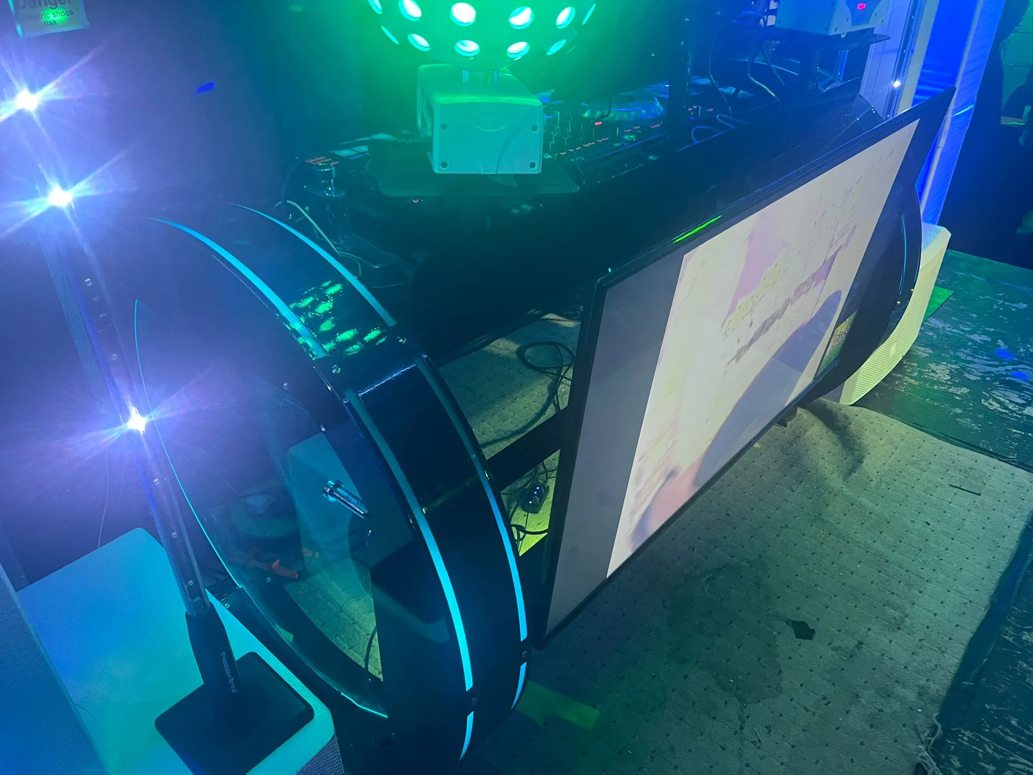 Professional DJ setup with a large display screen, illuminated by blue and green LED lights, perfect for an unforgettable party.