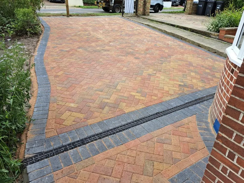Newly installed block paving driveway with multi-tonal blocks, dark grey border, and drainage channel by Top Pave Driveways LTD.