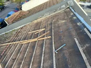 Roofing work in progress, showing wooden battens and a hammer on a roof during a new roof installation or replacement.