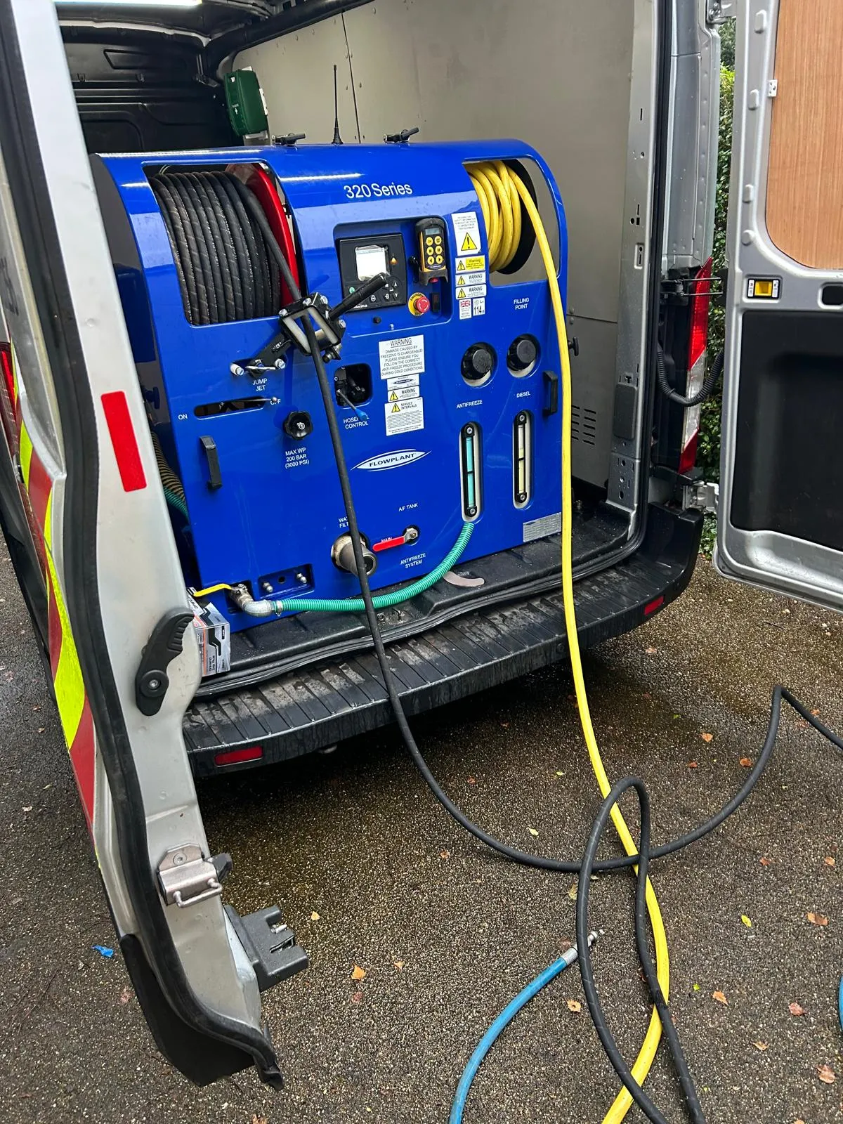 High-pressure water jetting equipment inside a Drains2Flow service van with hoses deployed for drain unblocking.