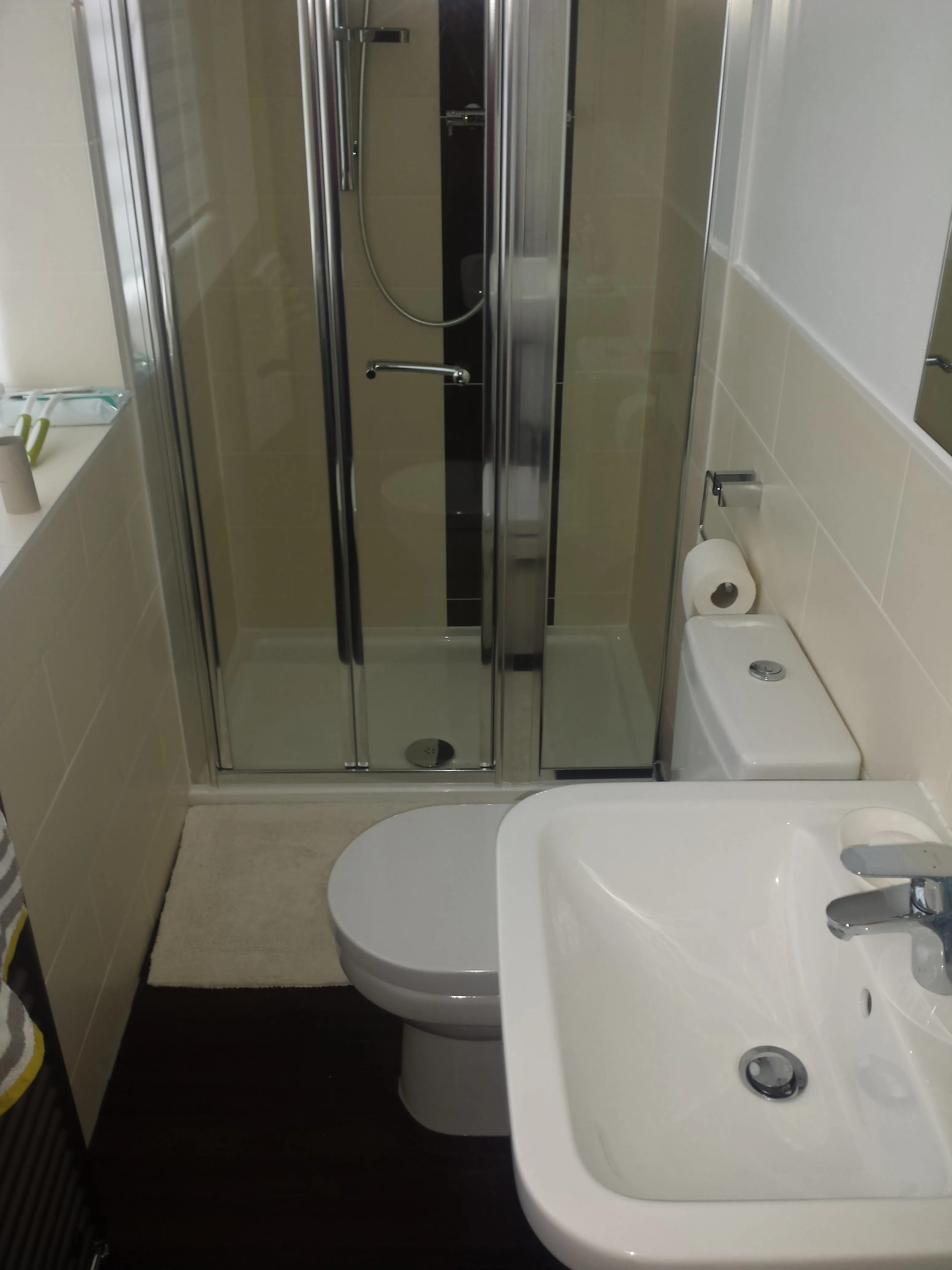 A compact and modern bathroom with a glass shower enclosure, a white toilet, and a sink with chrome fixtures.