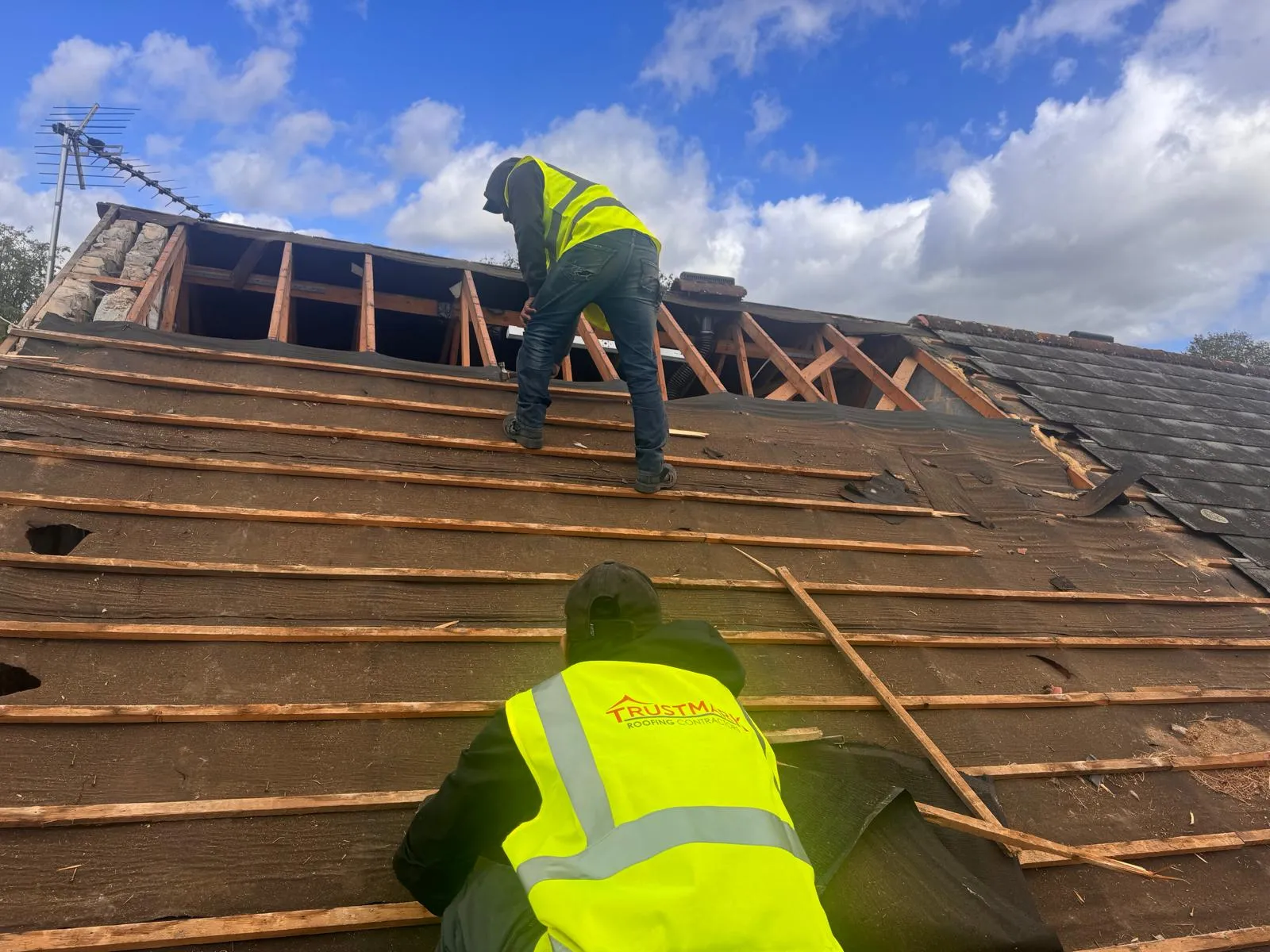 Trustmark Roofing contractors installing new battens and underlayment on a pitched roof during a re-roofing project.