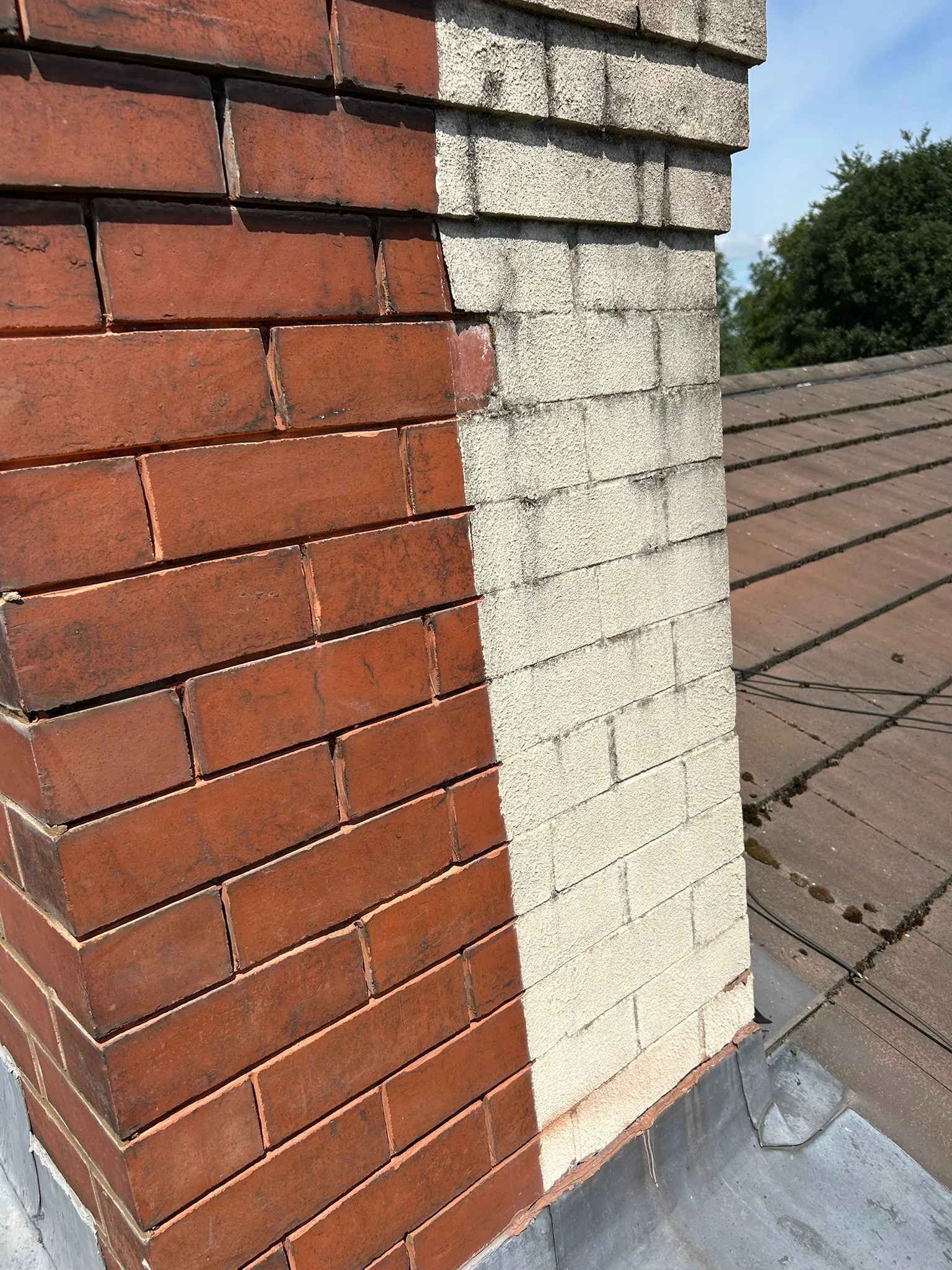 Chimney half cleaned and half dirty, showing red brickwork restored next to an uncleaned rendered section.