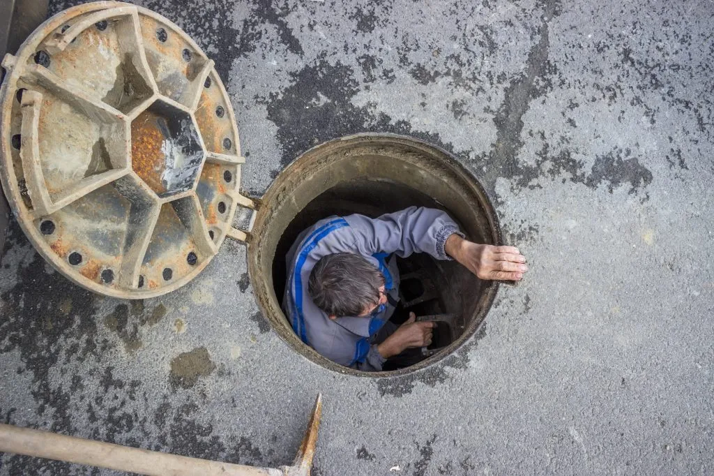 Drainage engineer inspecting or repairing a sewer system from inside a manhole.