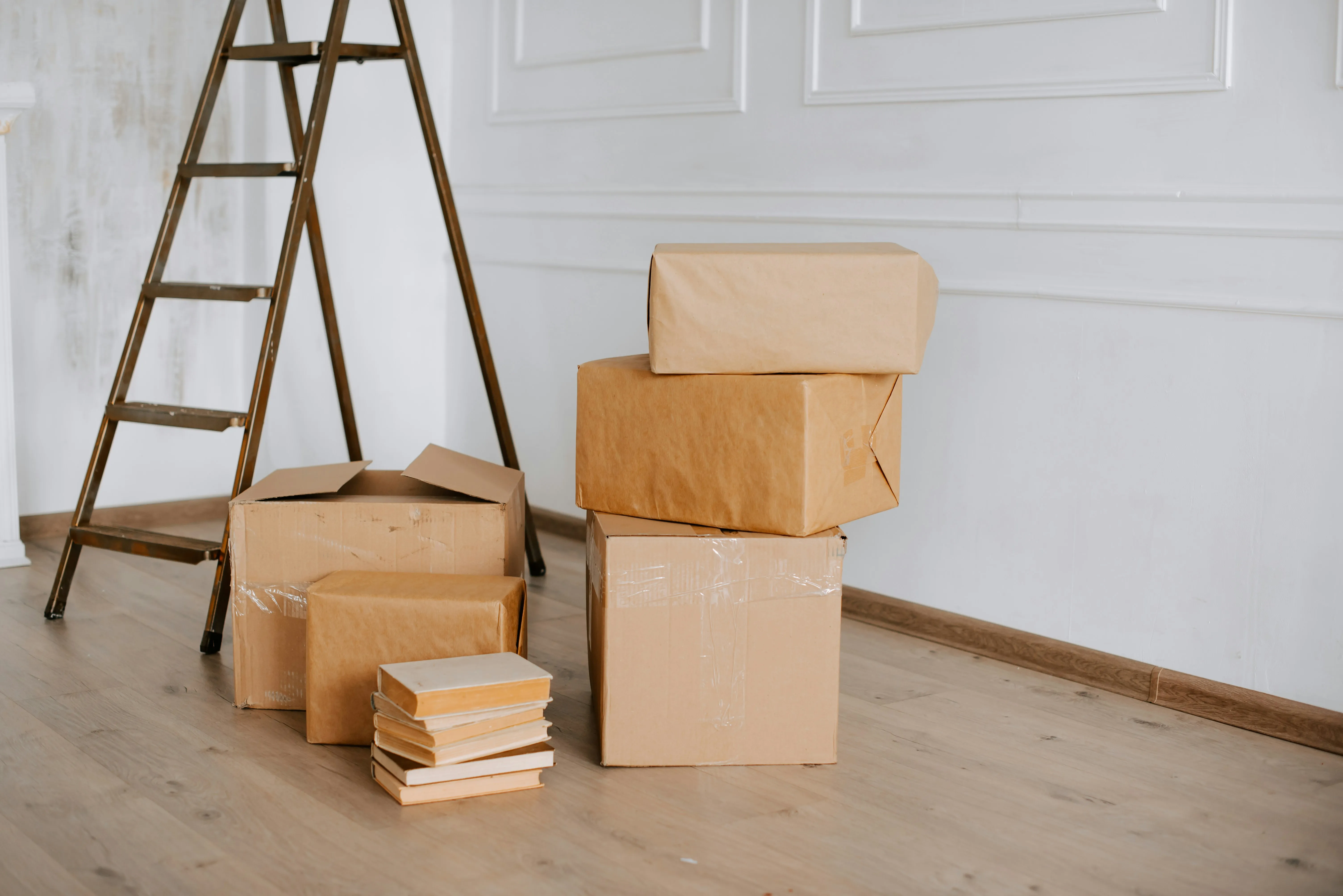 Packed moving boxes and books on floor in a room