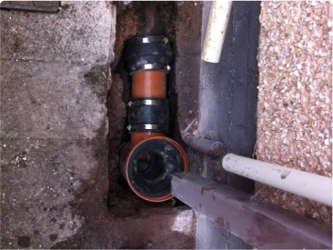 Newly installed section of underground drainage pipe showing connections and couplings in an excavated area.