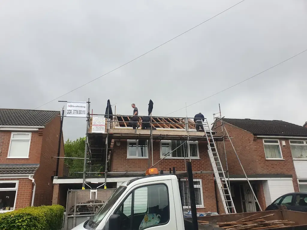 Roofers on scaffolding working on a residential house roof.