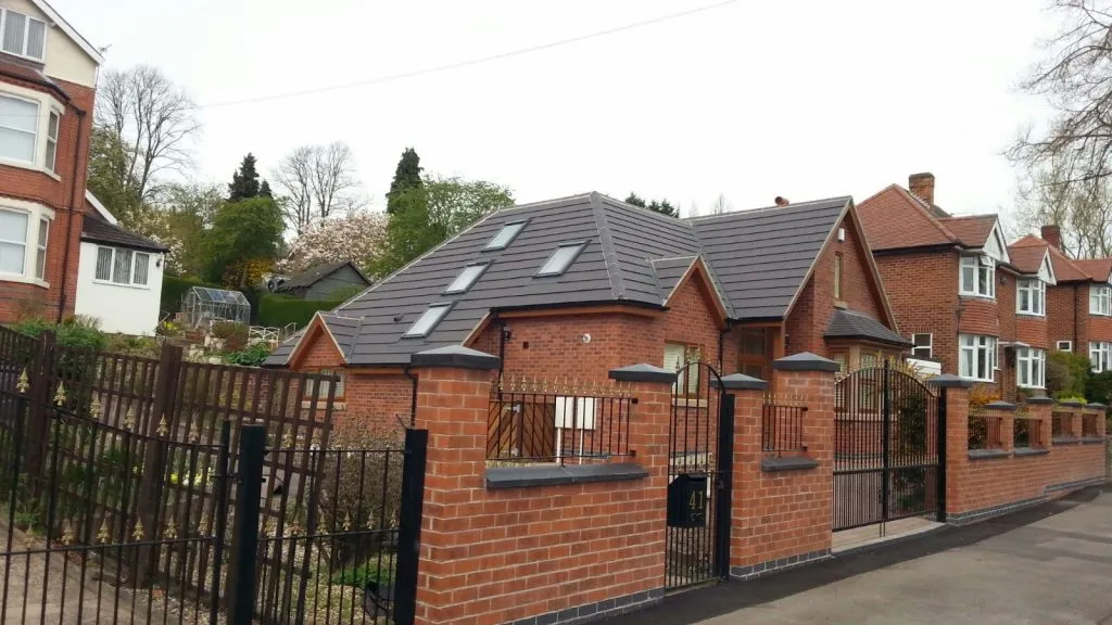 Newly installed dark grey pitched roof with multiple Velux windows on a modern brick house.
