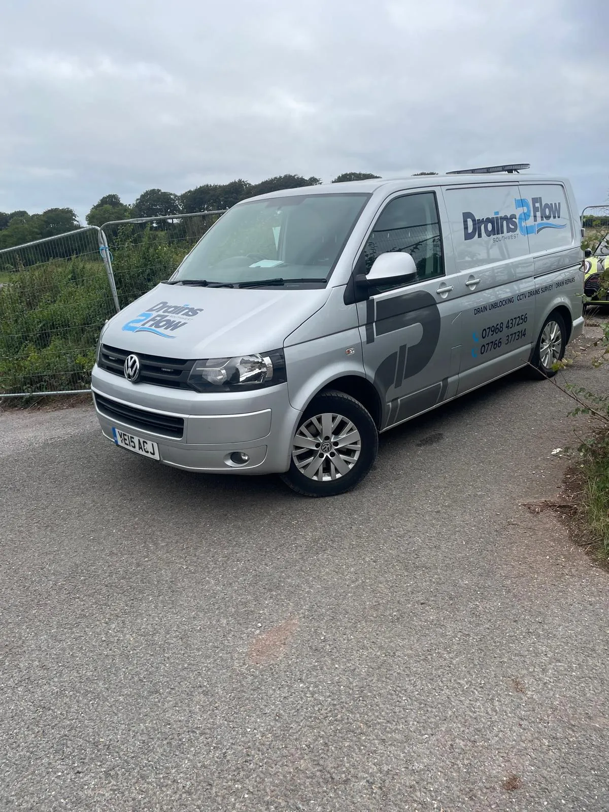 Drains2Flow company service van parked on a rural road, showing company branding and services offered.