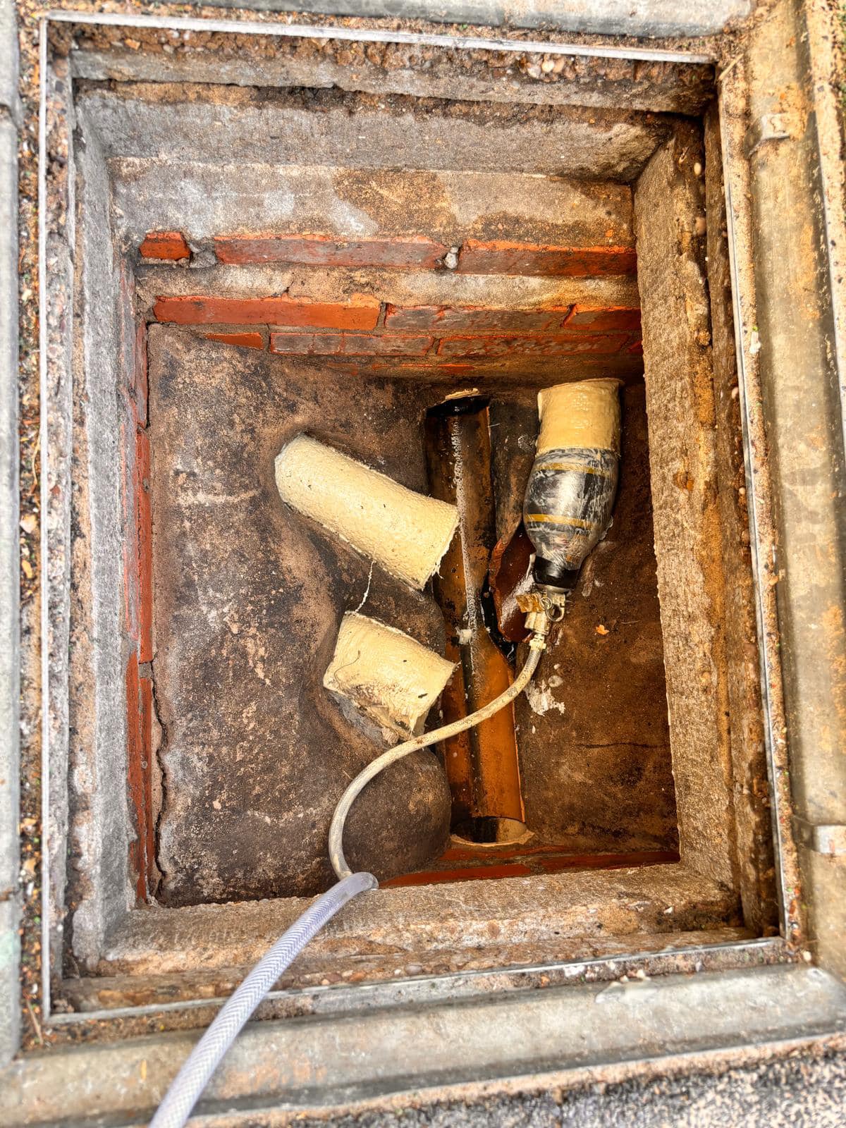 A Drain 2 Flow Torquay engineer using no-dig technology for drain relining or patch repair inside a drainage inspection chamber.