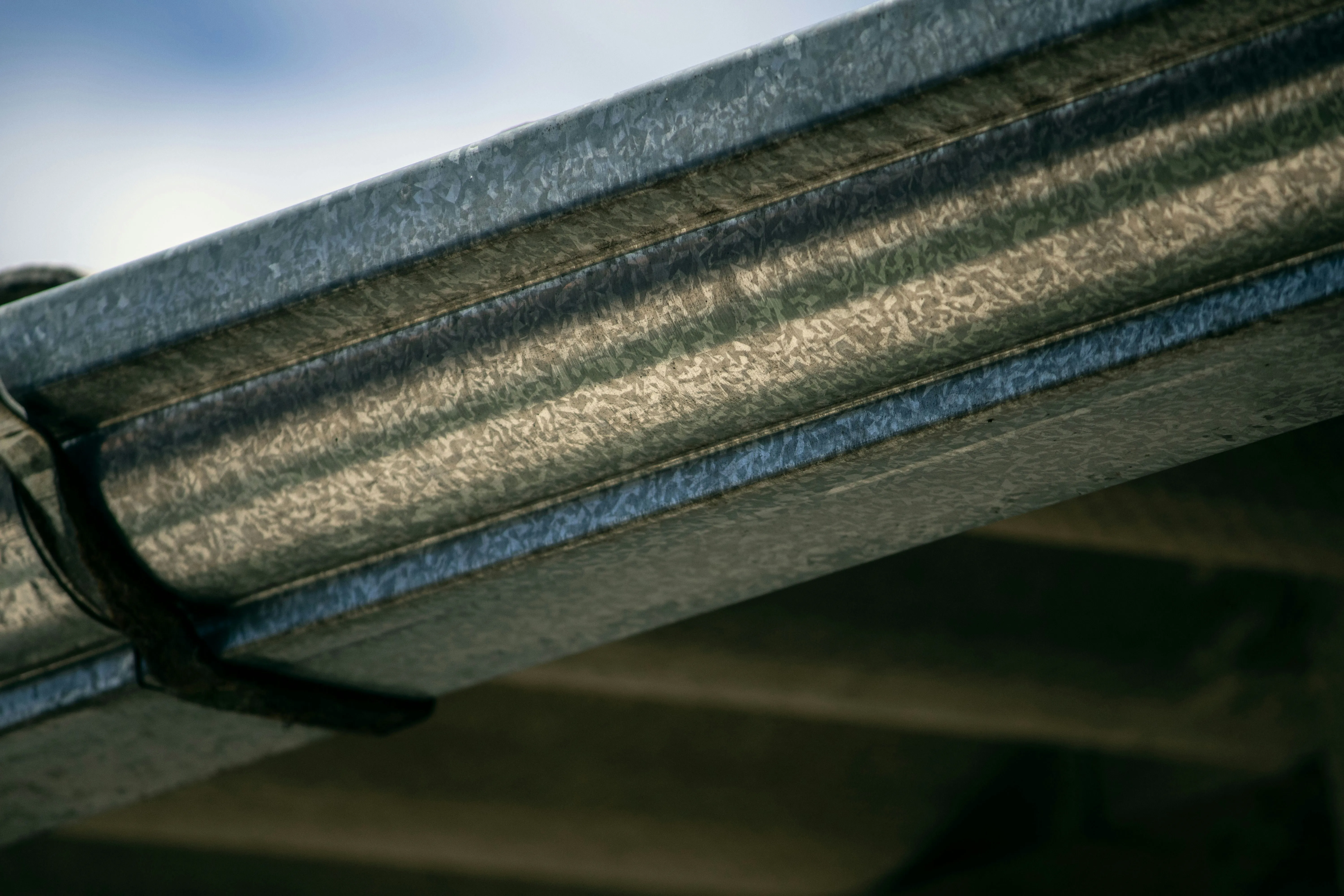 Close-up of new corrugated galvanised metal roofing sheets with a gutter bracket, ready for a garage roof installation in Spalding or Peterborough.