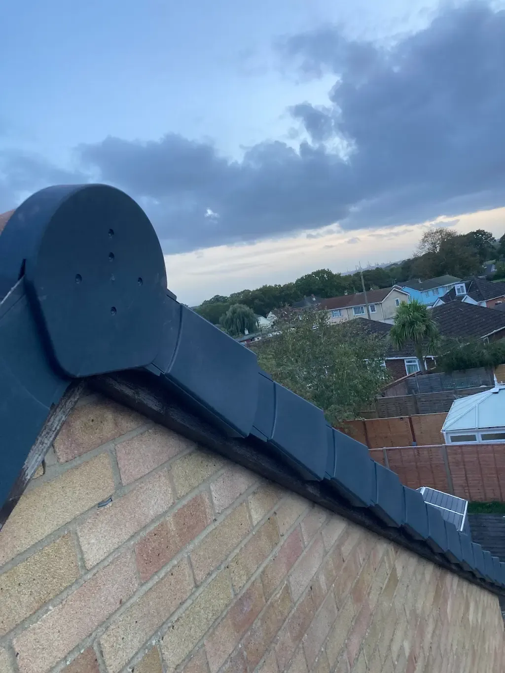 Close up of a tiled roof verge with a modern grey dry verge system and end cap installed.