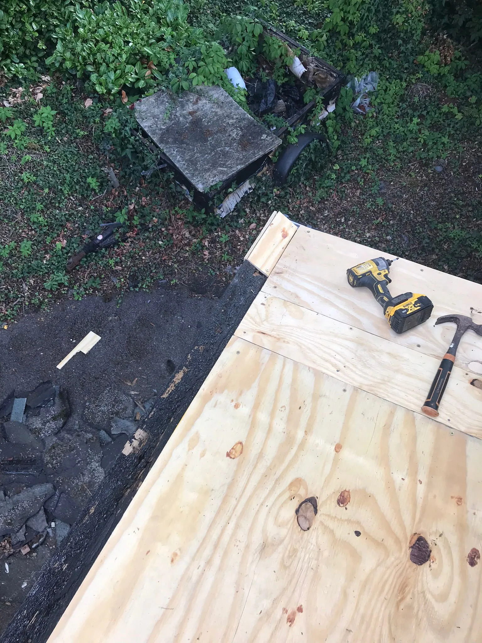 Flat roof re-decking in progress with new plywood, a drill, and a hammer.