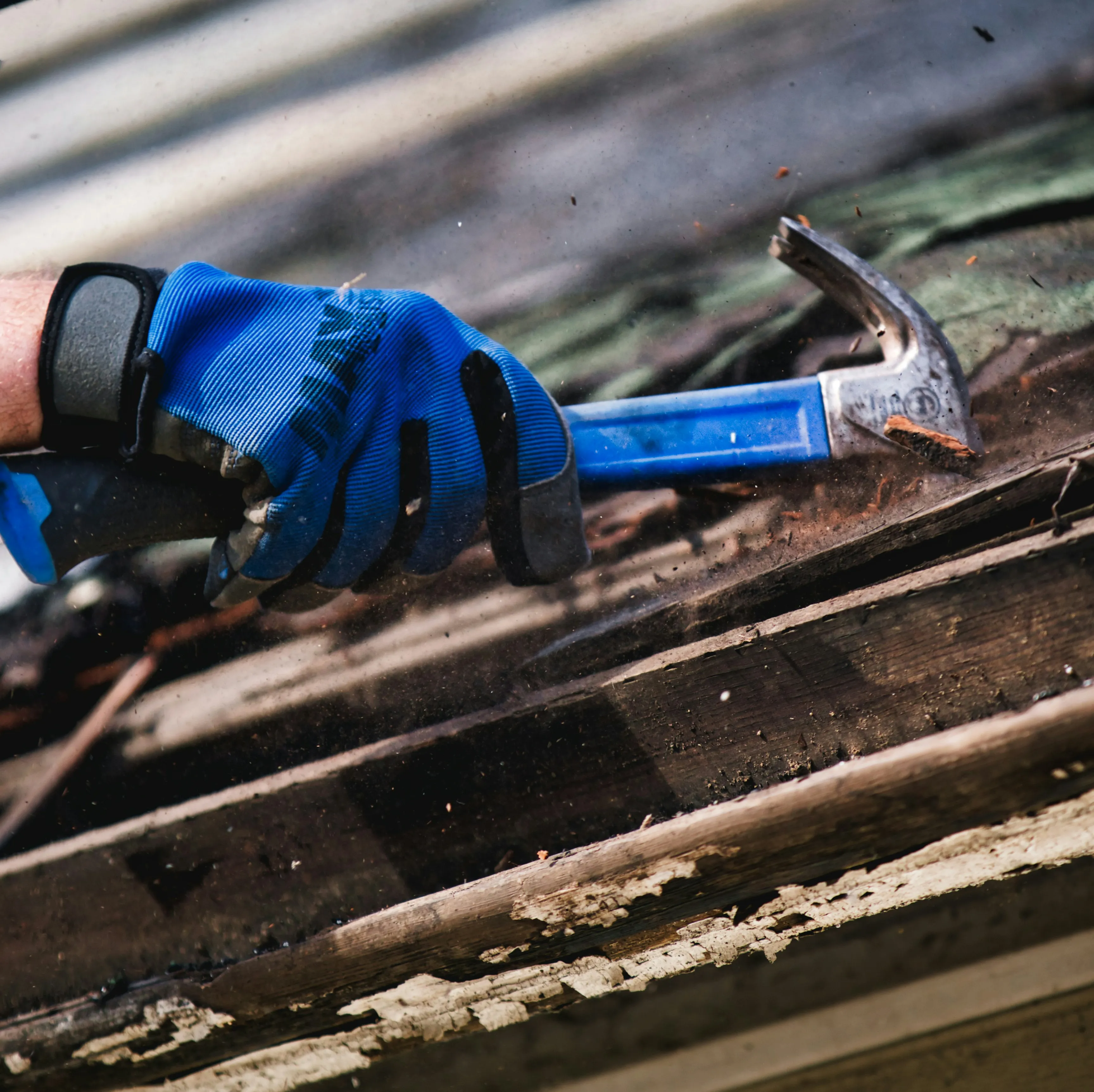 Roofer stripping old roof material with a hammer for a new roof installation or replacement.