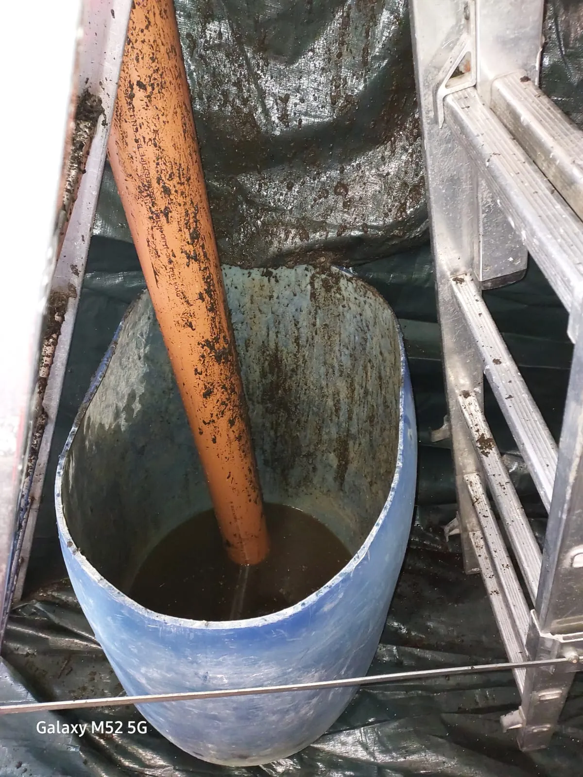 Waste water and debris being collected from a pipe during drainage work.