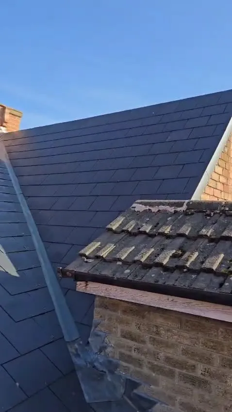 Contrast between new dark roof tiles and old mossy tiles on a residential roof, with visible lead valley and chimney lead flashing.