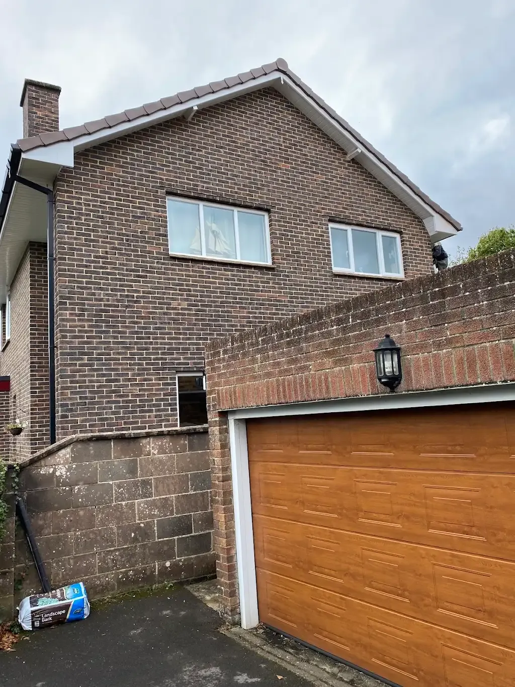 Exterior view of a residential house with a pitched tiled roof, chimney, fascias, soffits, guttering, and garage.
