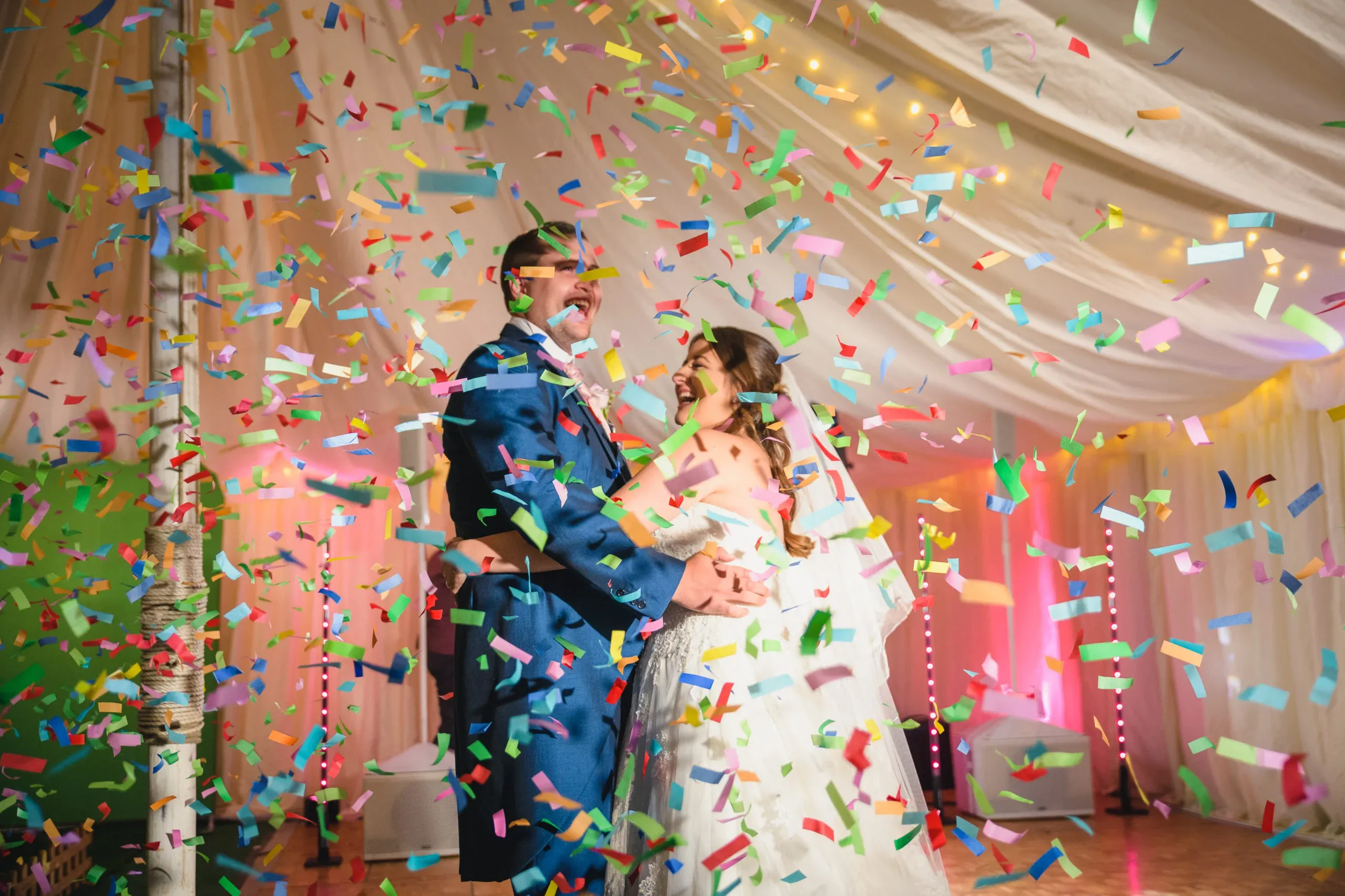 Ecstatic bride and groom celebrating with a colourful confetti cannon at their wedding reception, highlighting a fun and unforgettable moment provided by Disco Entertainers.