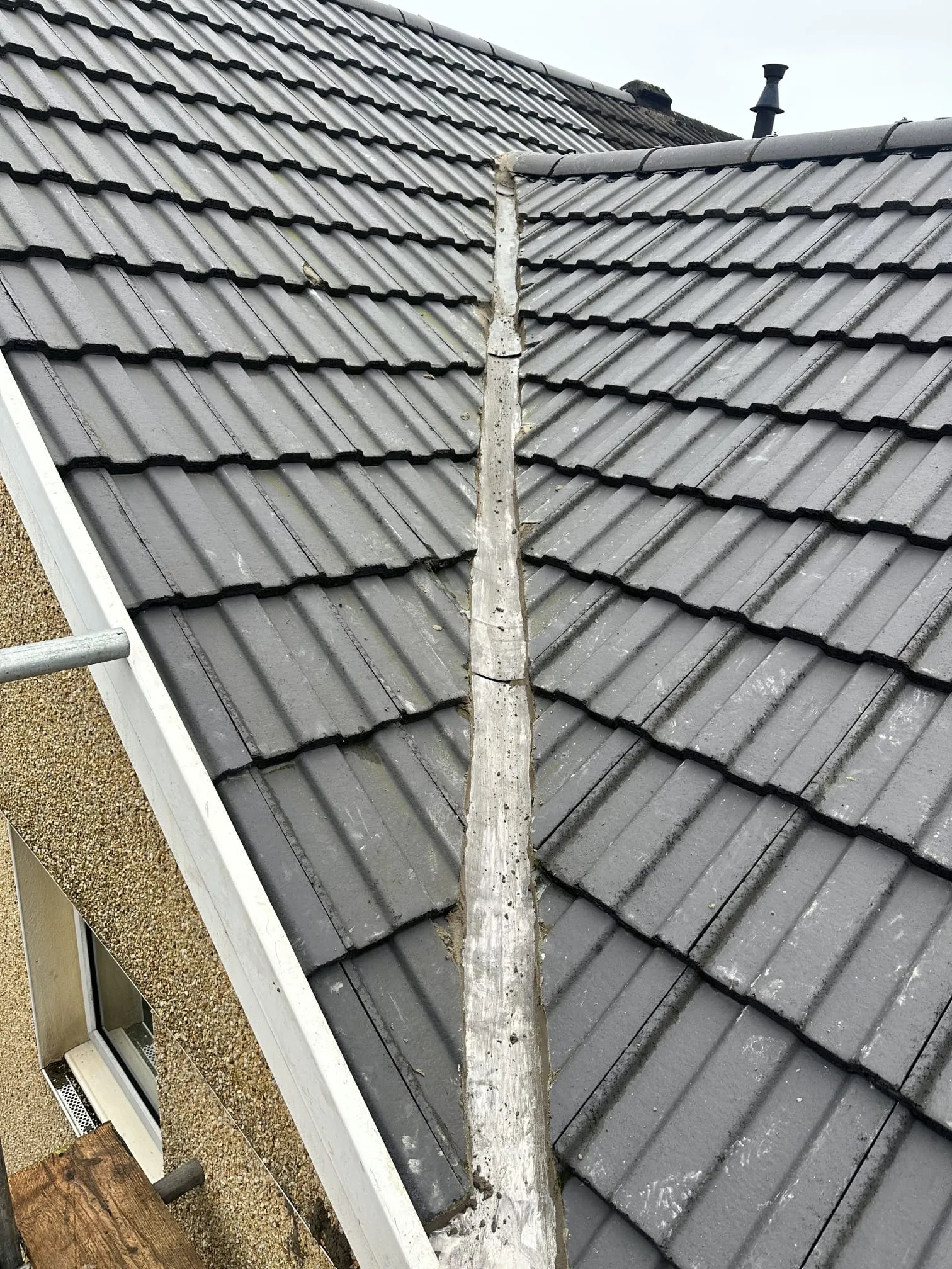 Tiled roof with a central valley and scaffolding visible on the side.