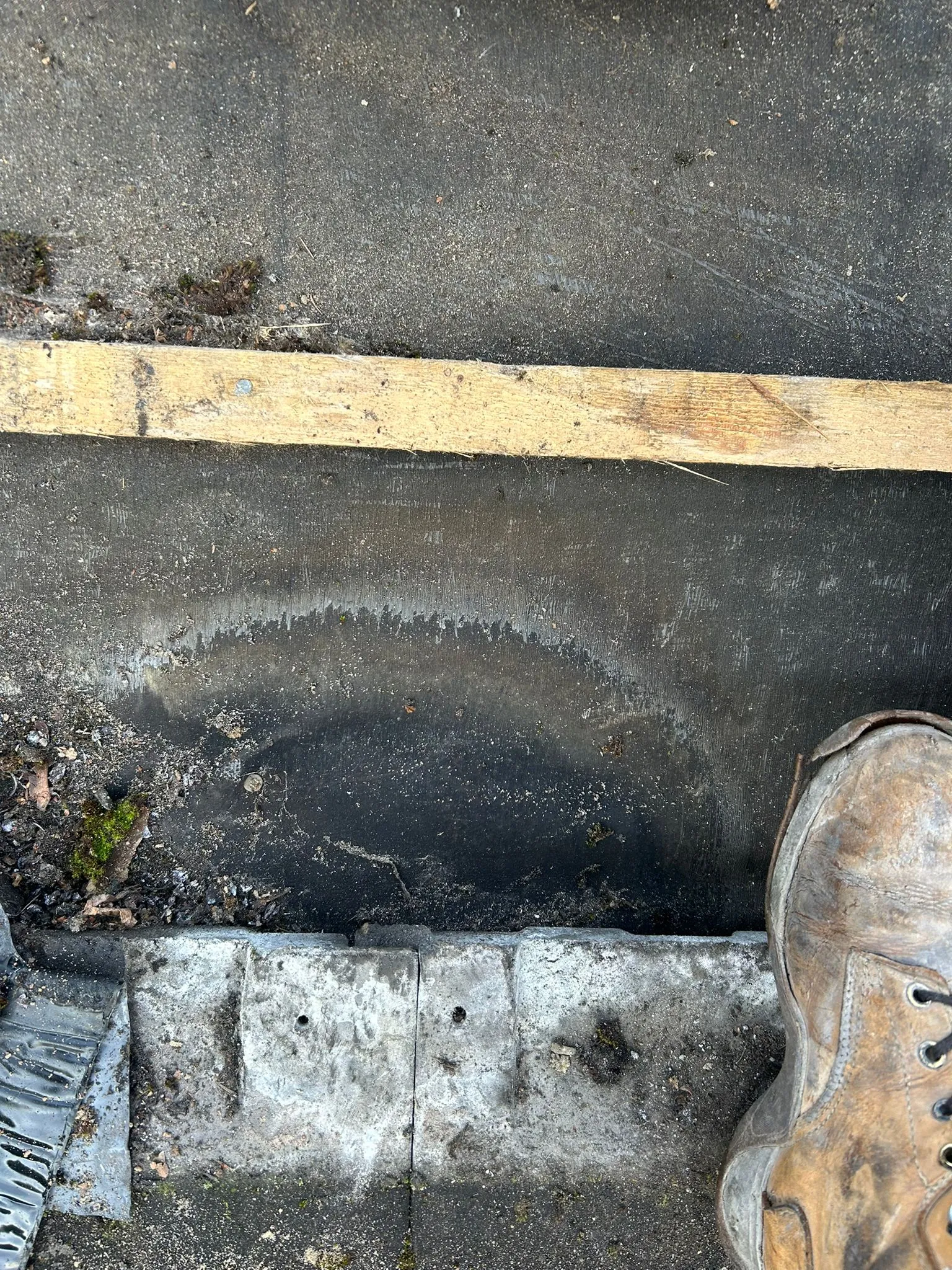 A flat roof with debris and water stains, suggesting a blocked drain