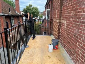 Roofer working on the plywood base of a flat roof or balcony, preparing for new installation.