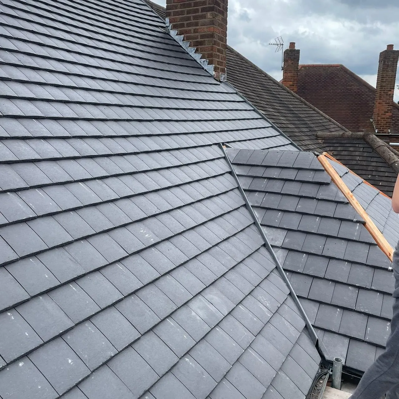 Newly installed dark grey tiled roof with lead valley and chimney flashing