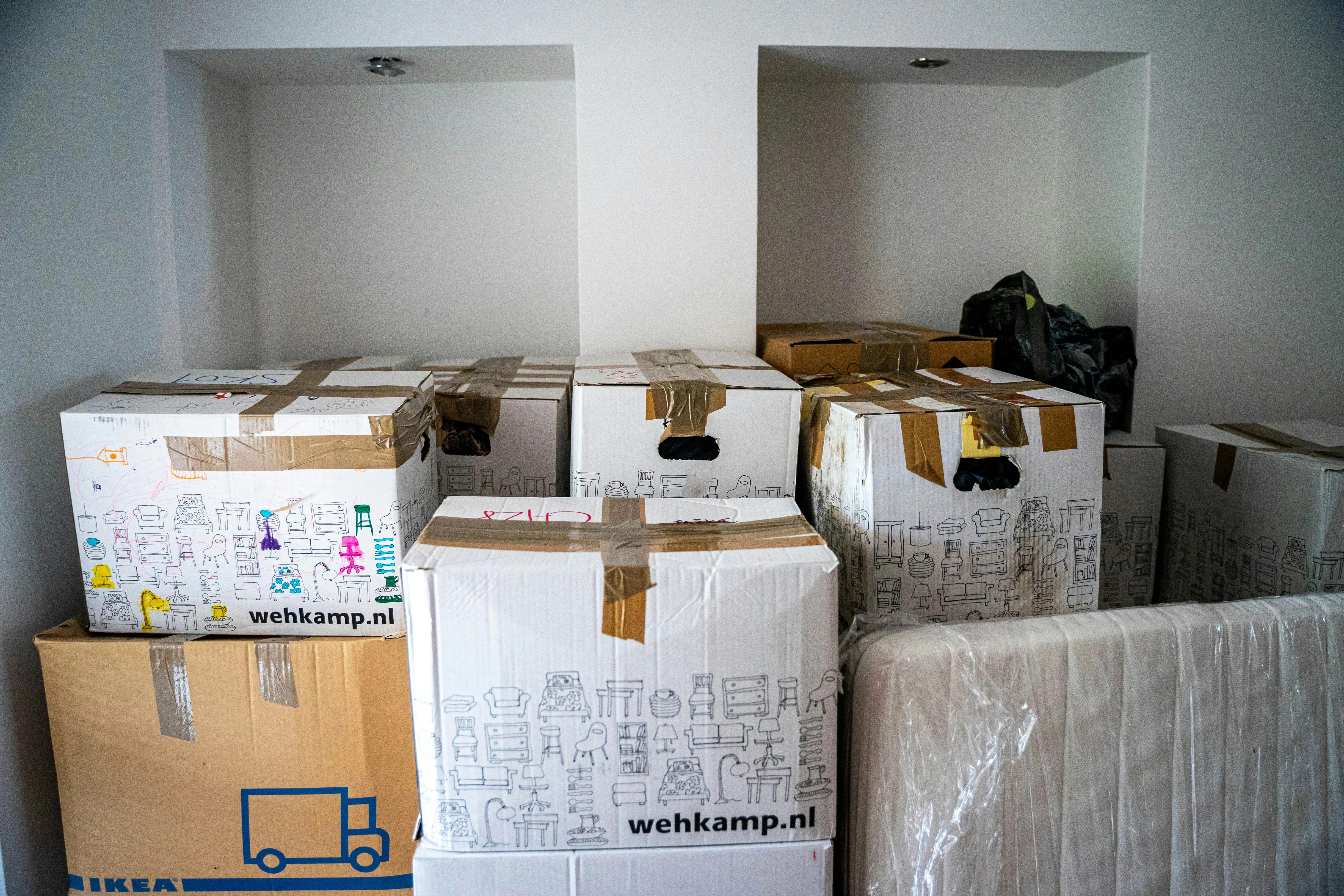 Stacked moving boxes with furniture illustrations, ready for a house move.