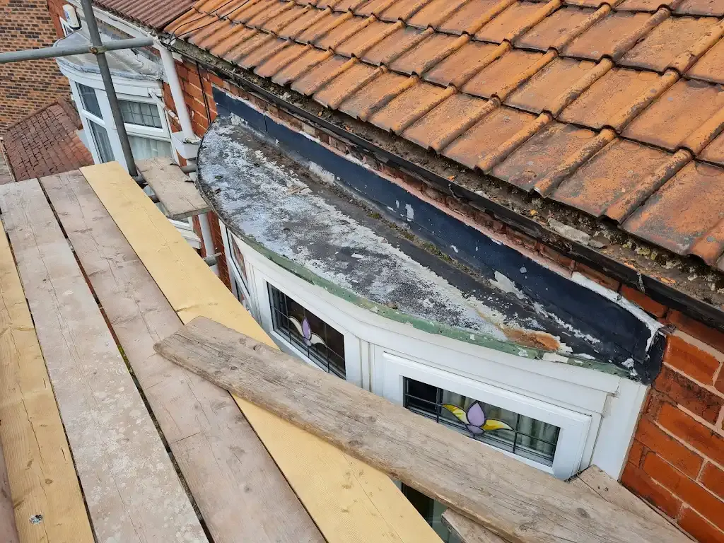 Damaged residential flat roof above a bay window needing repair