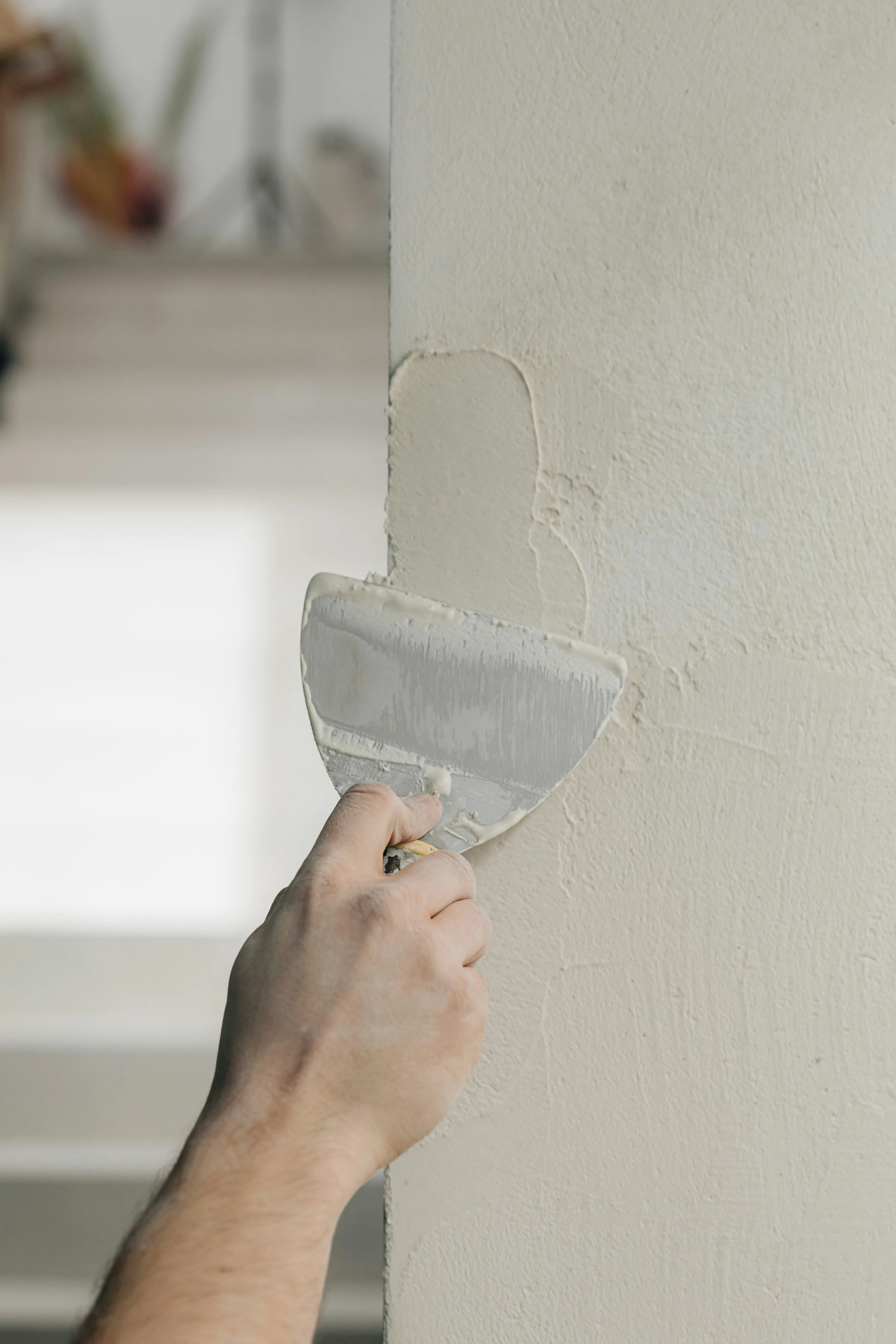 Professional plasterer smoothing internal wall plaster with a trowel.