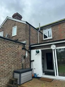 Rear view of a house showing brickwork, a flat roof extension, and newly installed or well-maintained fascias, soffits, and guttering system.