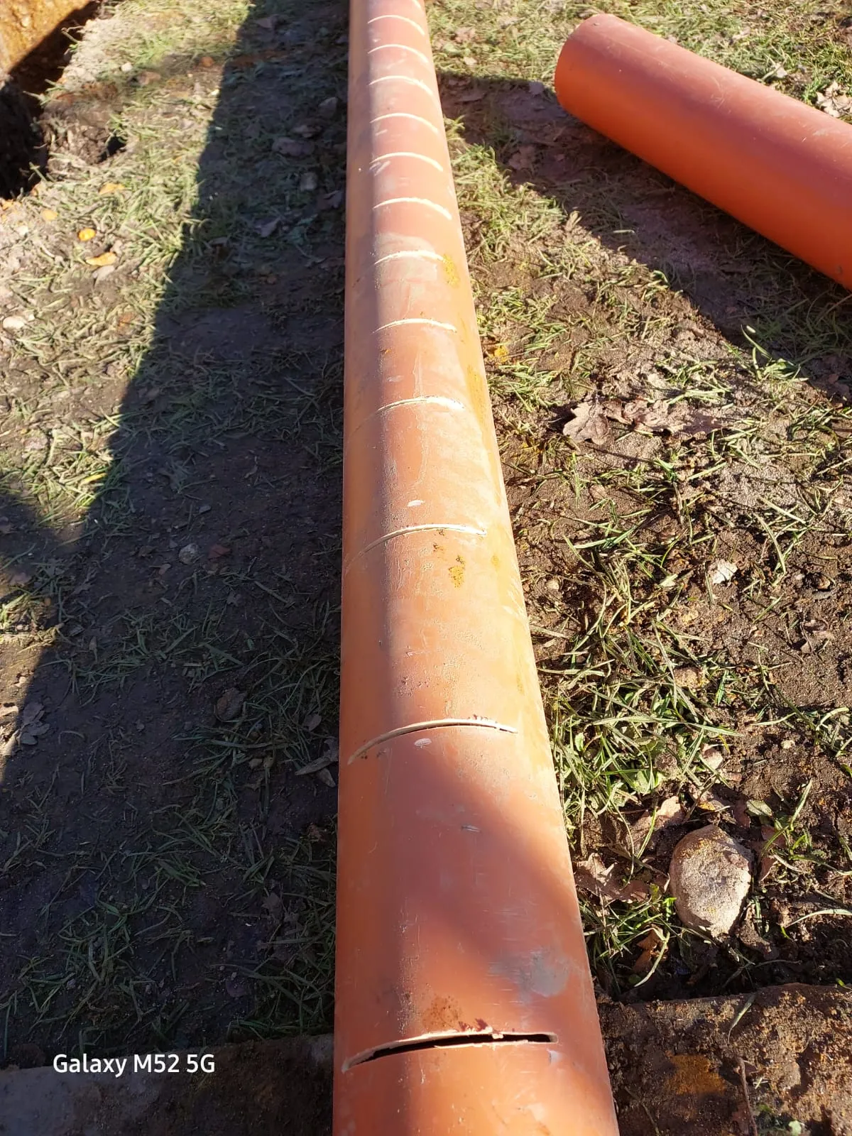 Orange drainage pipes for soakaway or storm line installation on the ground